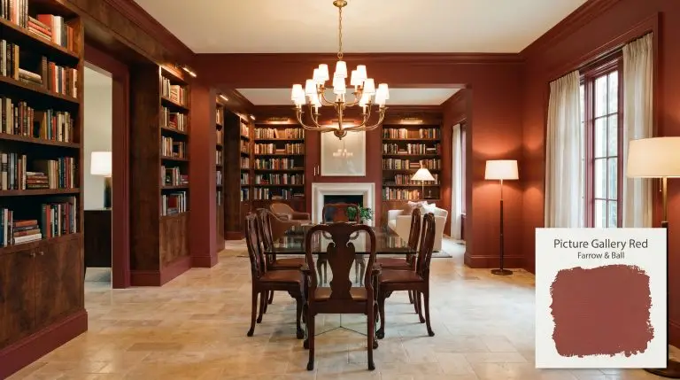An open-plan home library and formal dining area painted in Farrow & Ball Picture Gallery Red (Hex #9b594f) features rich walnut burl veneer shelving, a sleek glass dining table, heavy carved mahogany chairs, and tumbled travertine flooring.