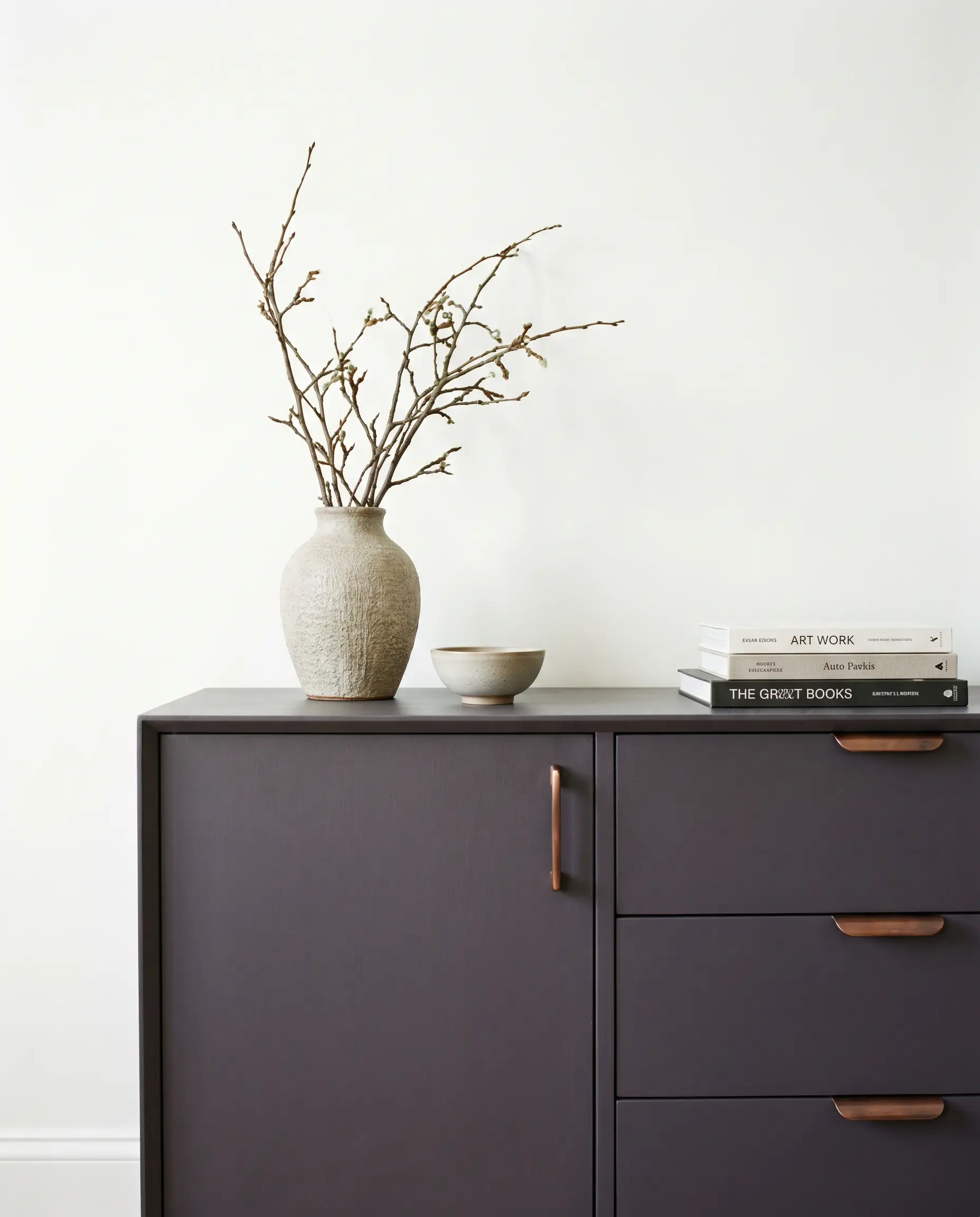 A mid-century modern credenza finished in a royal amethyst hue features clean architectural lines and updated antique copper pulls against a crisp white wall.