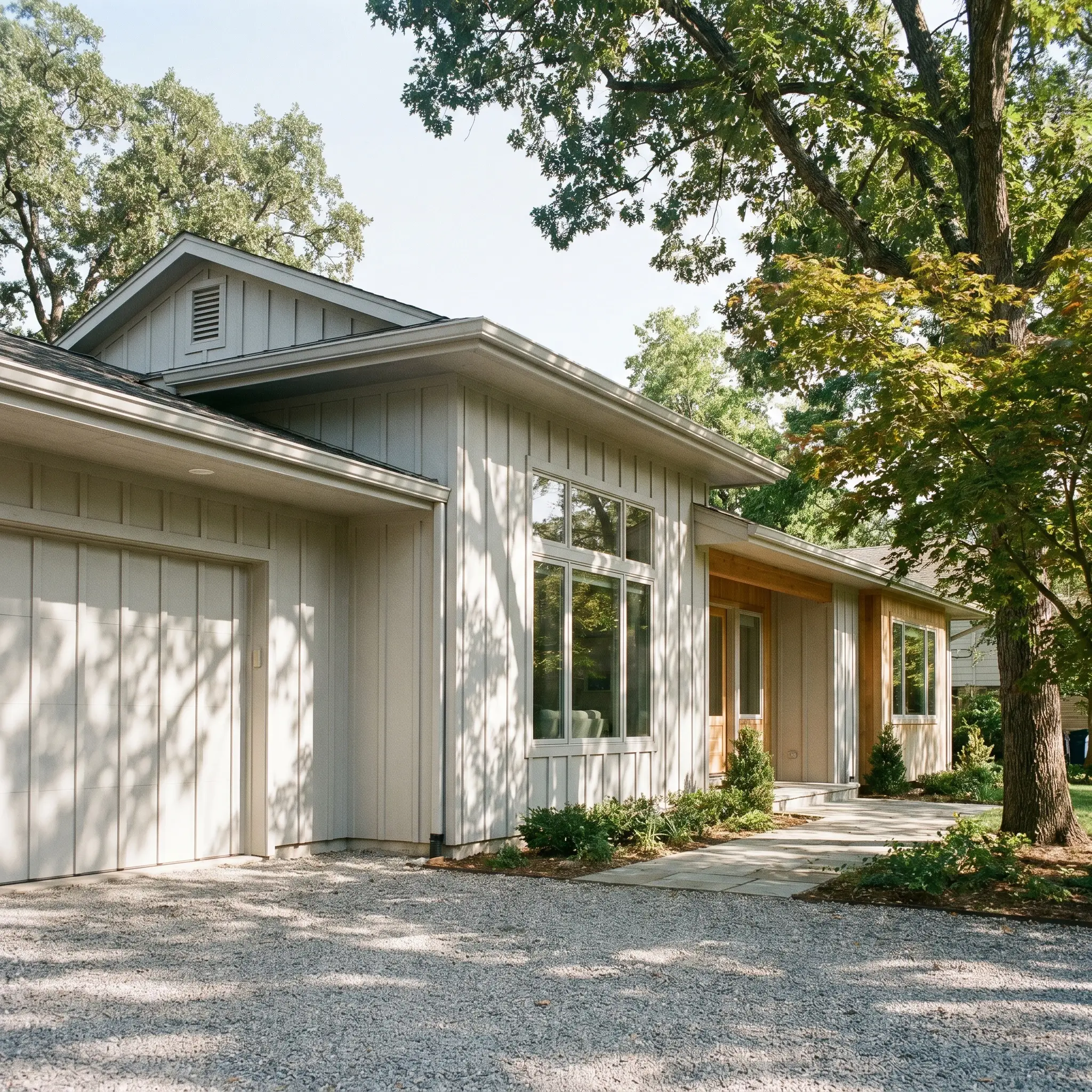 Deep eaves cast strong architectural shadows over textured board and batten siding painted in the cool gray neutral of Passive by Sherwin-Williams.