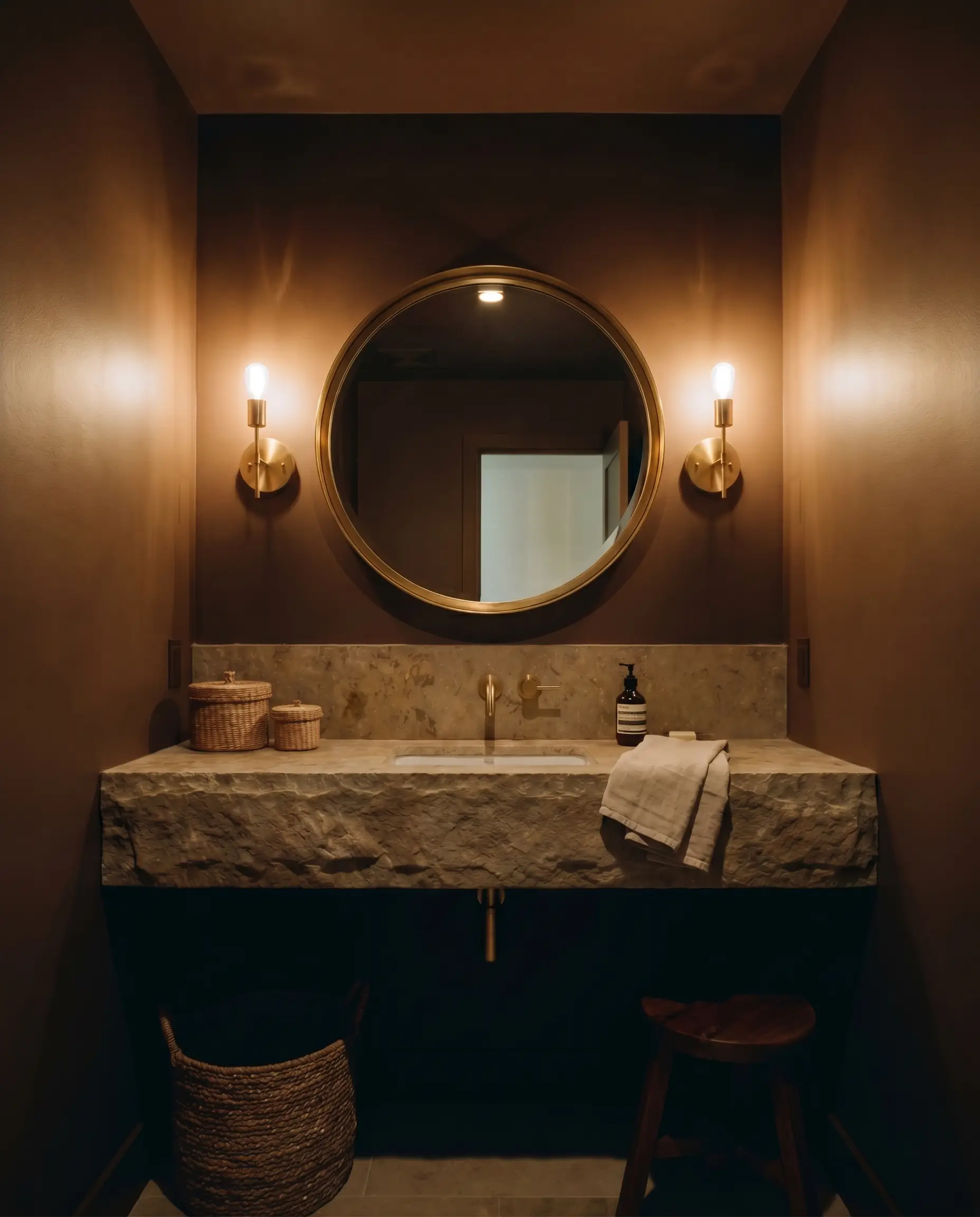 An oversized brass-framed mirror and natural stone vanity anchor a windowless powder room enveloped by Sherwin-Williams Clove walls and ceiling.
