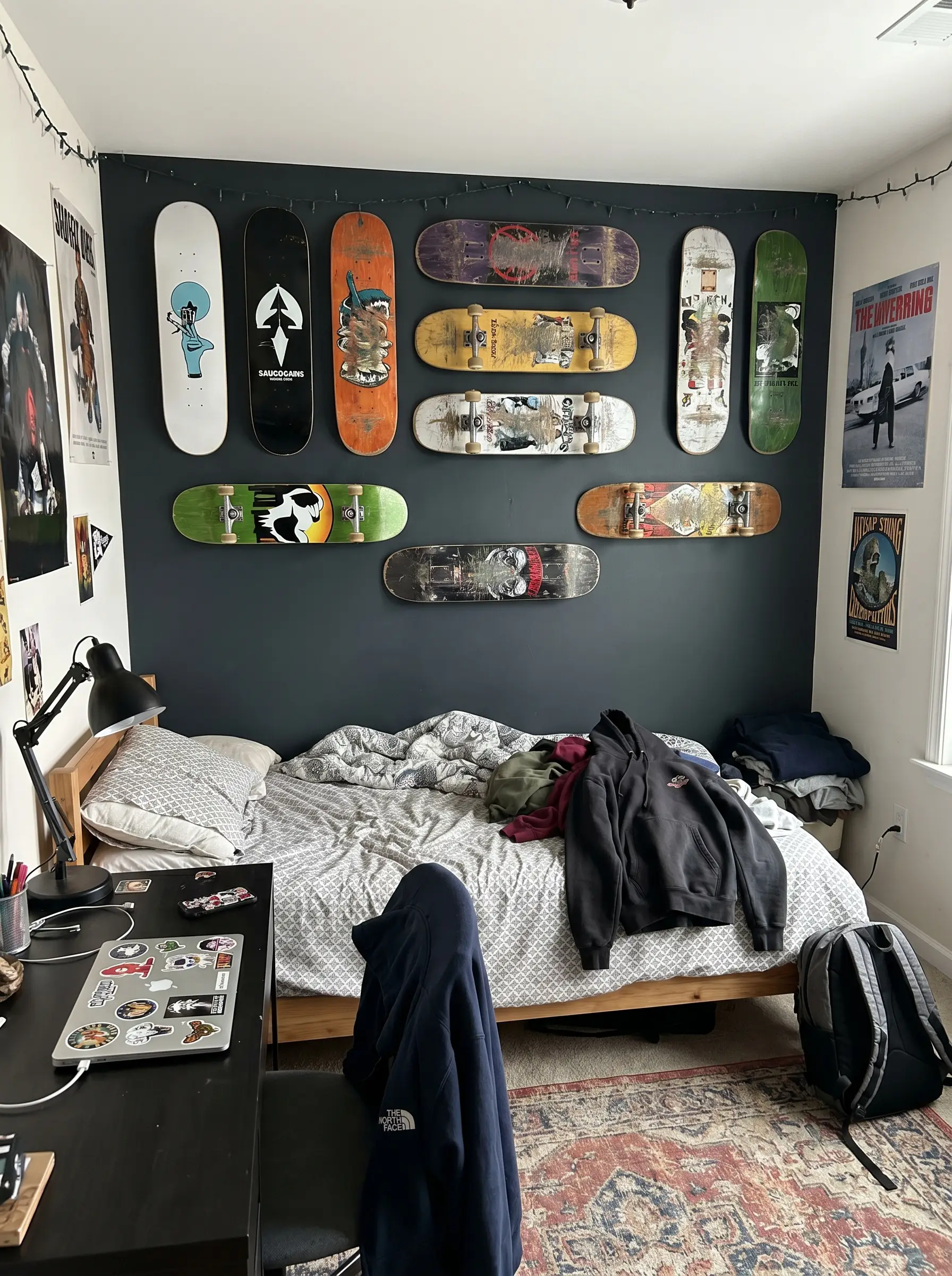 Graphic skateboard decks mount horizontally and vertically on a deep charcoal wall using invisible floating hardware in this aesthetic boy bedroom.