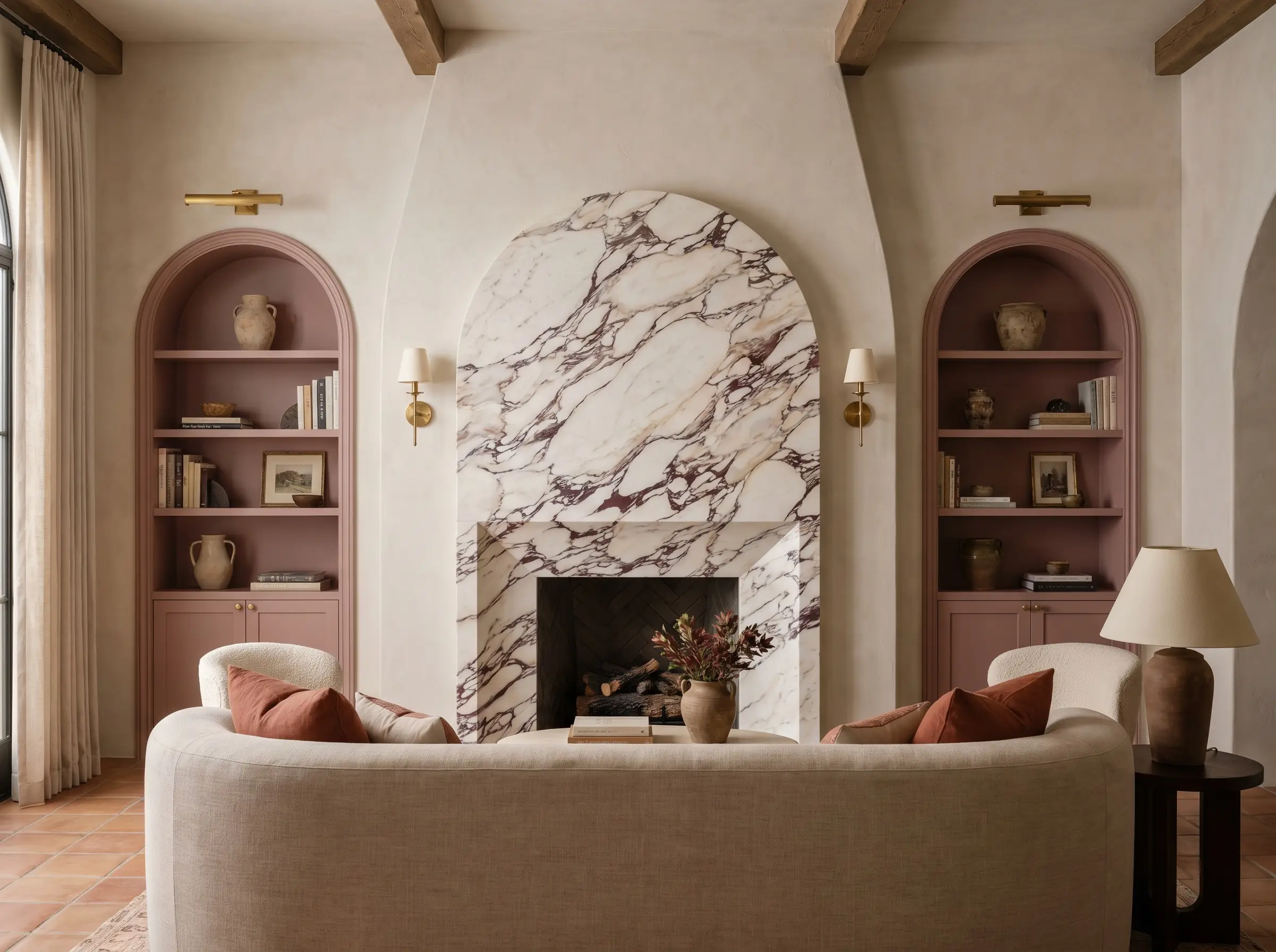 A custom-cut Calacatta Viola marble fireplace fascia shaped into a soft Roman arch is flanked by matching arched built-in bookcases and a curved linen sofa.