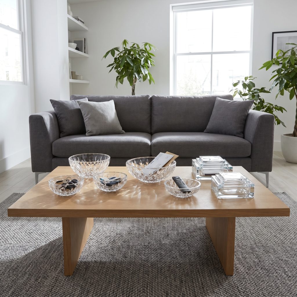 Art deco touches modern living room styling includes faceted cut lead crystal catchalls and stepped-glass boxes on a matte wood coffee table.
