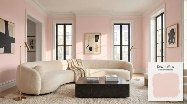 A luminous living room painted in Benjamin Moore Dream Whip (Hex #F4D7D1) featuring a curved boucle sofa, dark marble coffee table, and brass lamps.