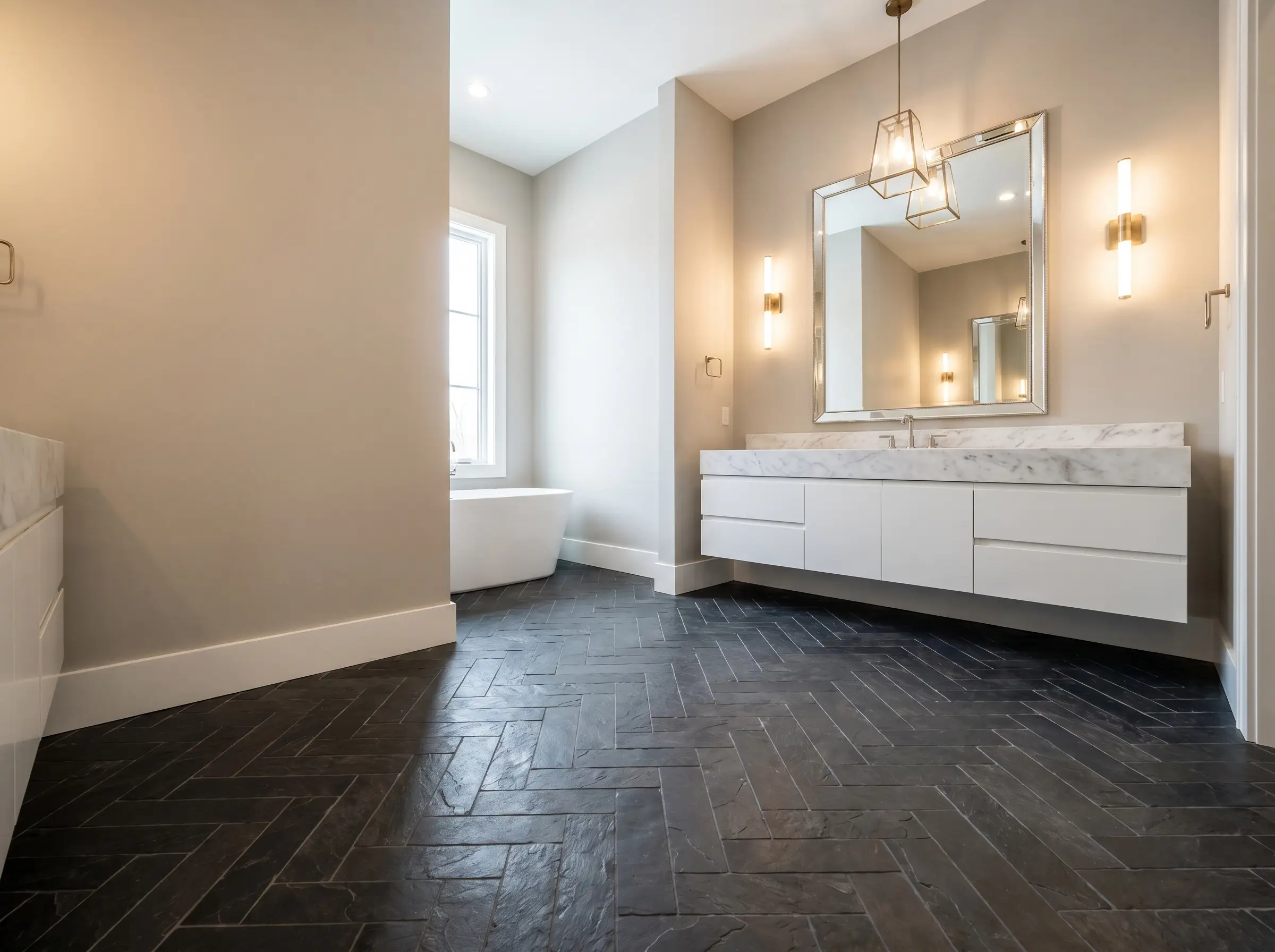 Natural clefted Montauk slate floor tiles laid in a precise herringbone pattern provide a dark architectural foundation for a crisp white vanity.