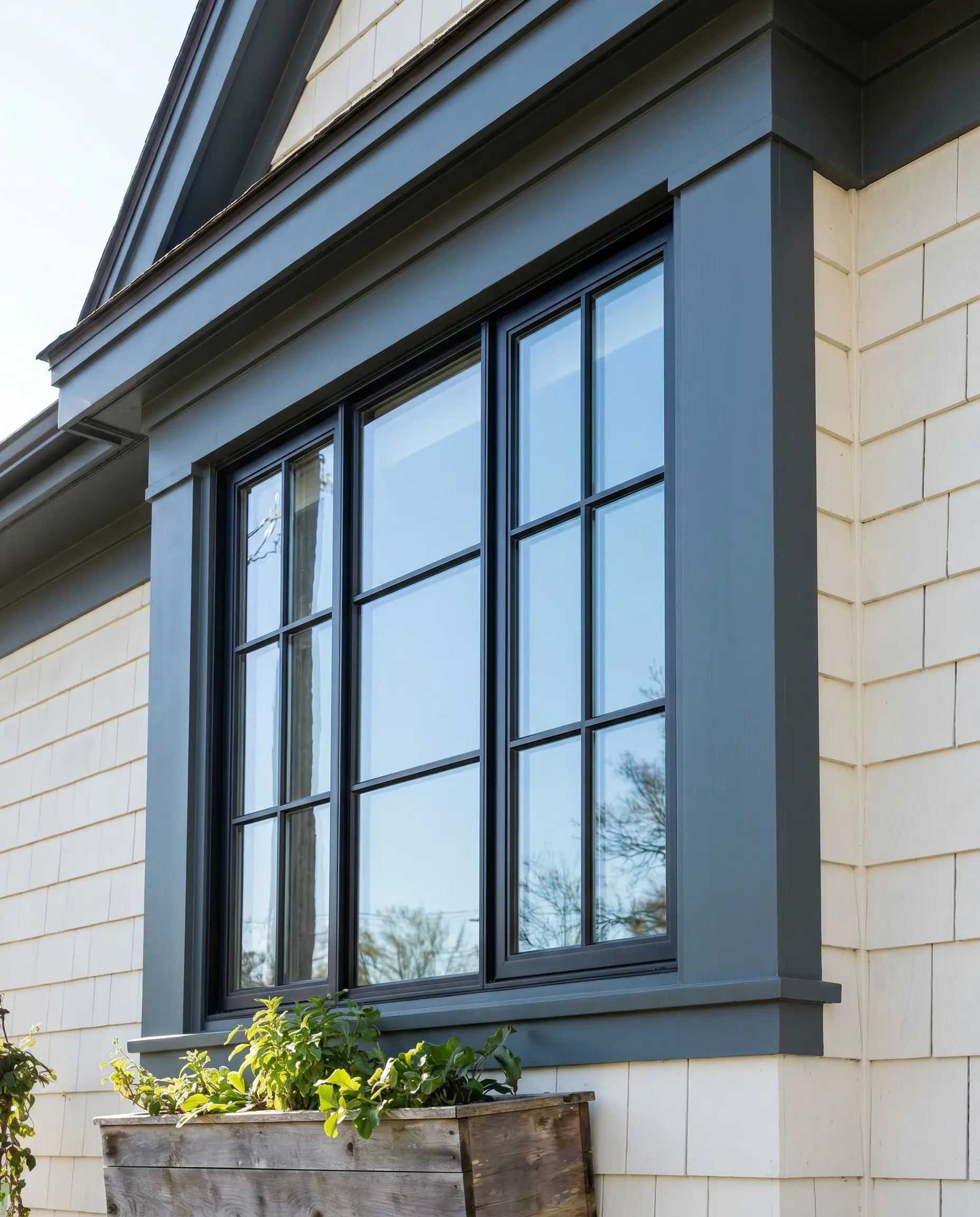 Contemporary industrial window trim painted in sophisticated soft black contrasts gracefully against soft neutral white siding on a custom multi-pane window.