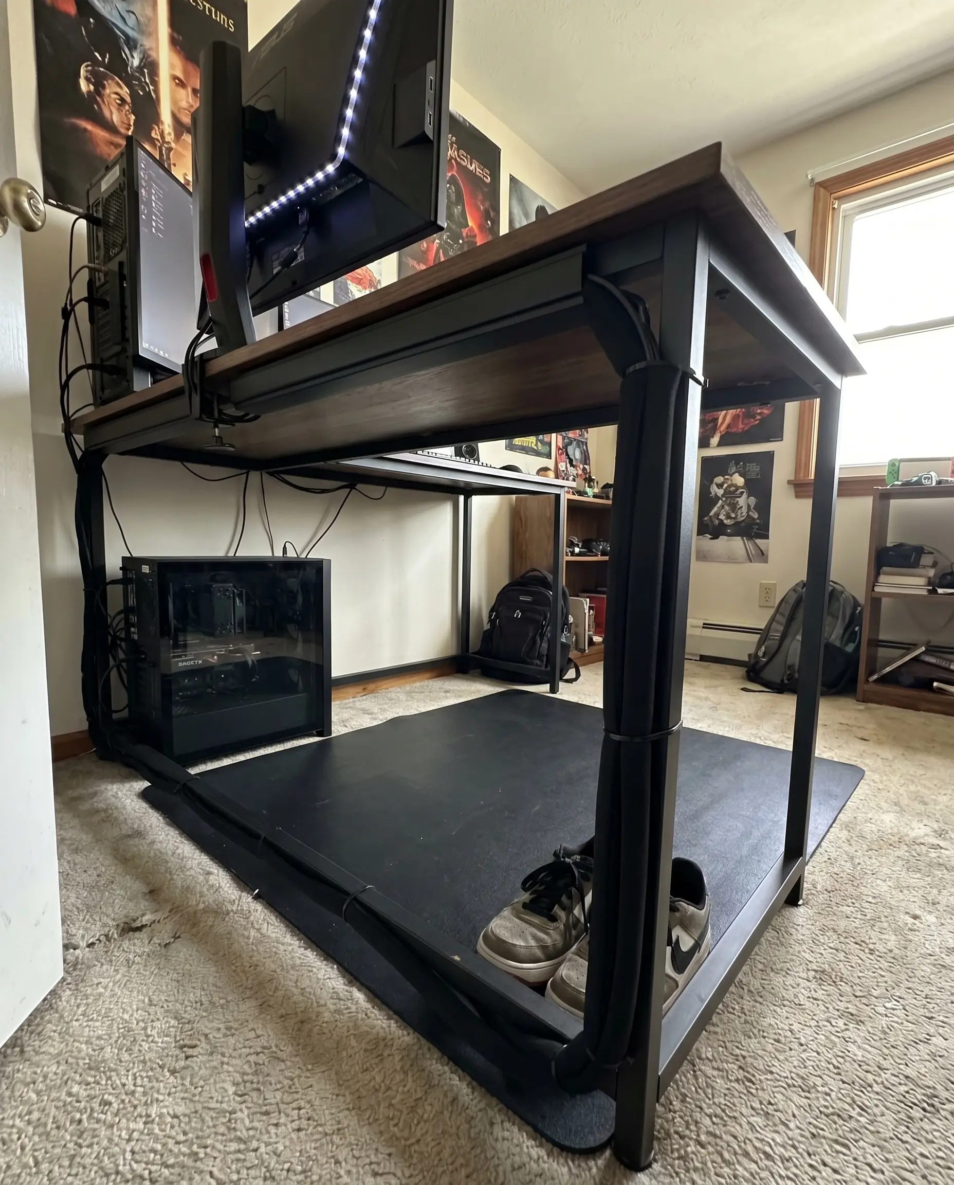 J-channel raceways and a black neoprene cable sleeve run down the leg of a gaming desk to hide hardware wires completely.