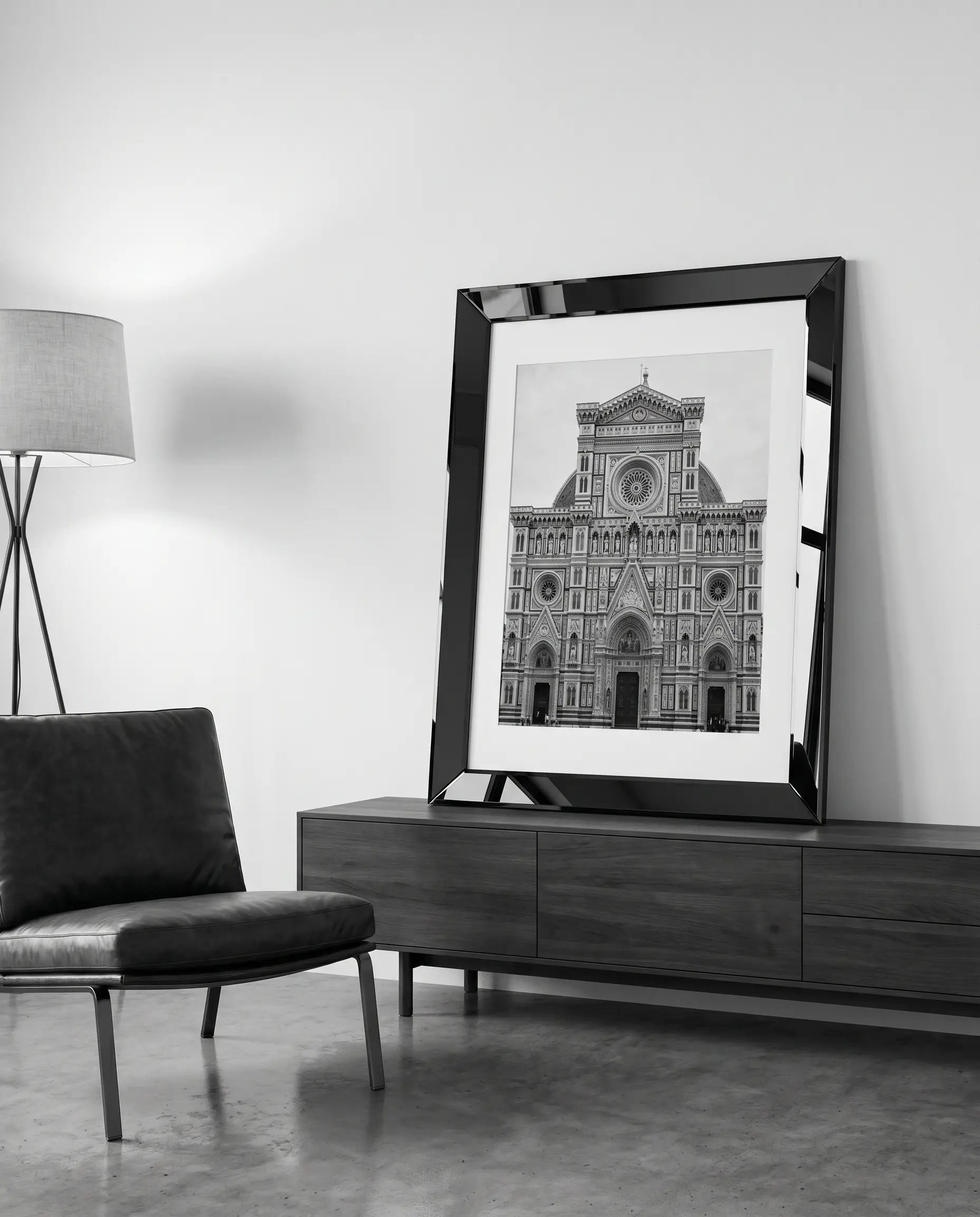 A large-scale black-and-white architectural photograph in a mirrored frame leans on a modern credenza against a Benjamin Moore Chantilly Lace white wall.