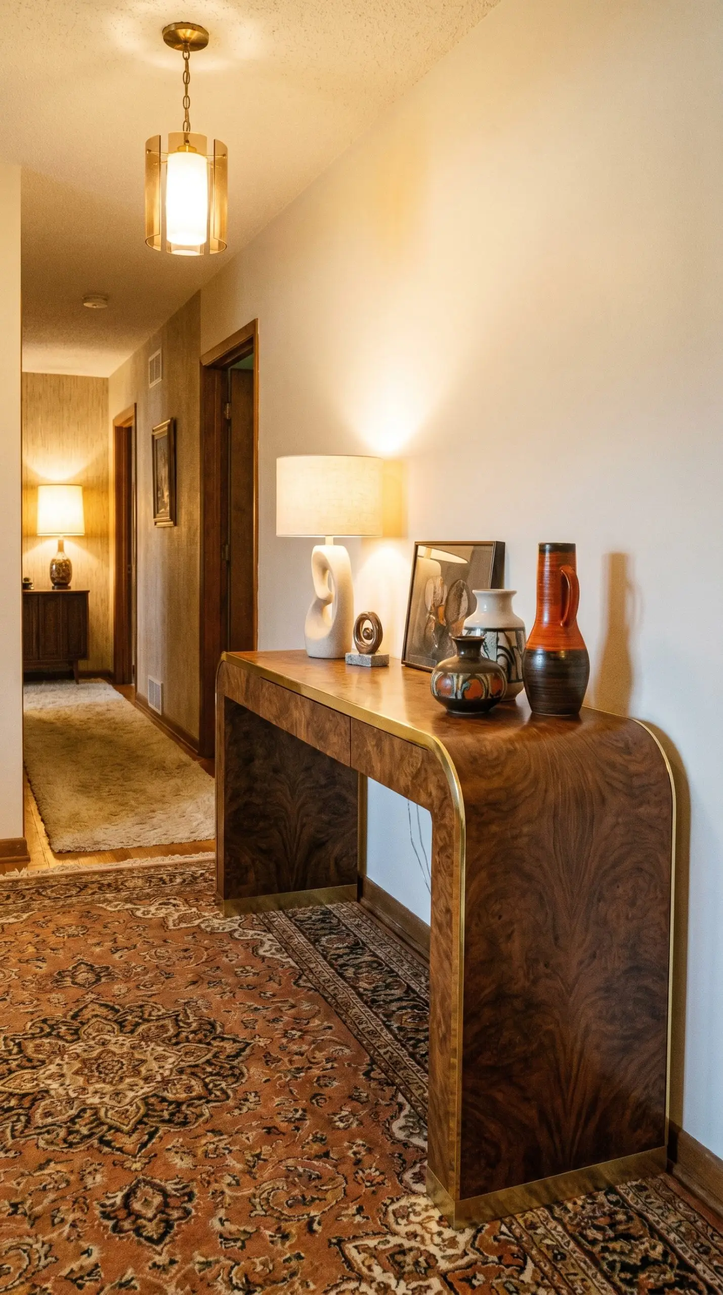 A vintage 1970s burled walnut console table showcases a flawless continuous waterfall edge with polished brass edging, styled with retro-modern artifacts.