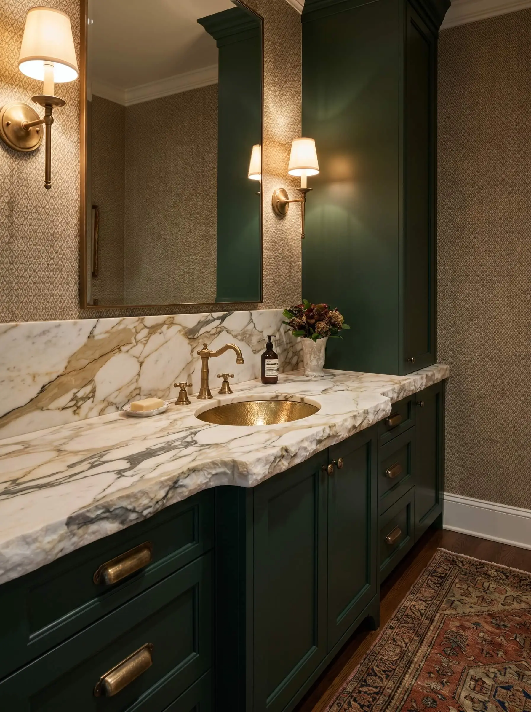 A premium calacatta borghini slab remnant tops custom deep forest green cabinetry adorned with vintage brass hardware and a deck-mounted brass faucet.