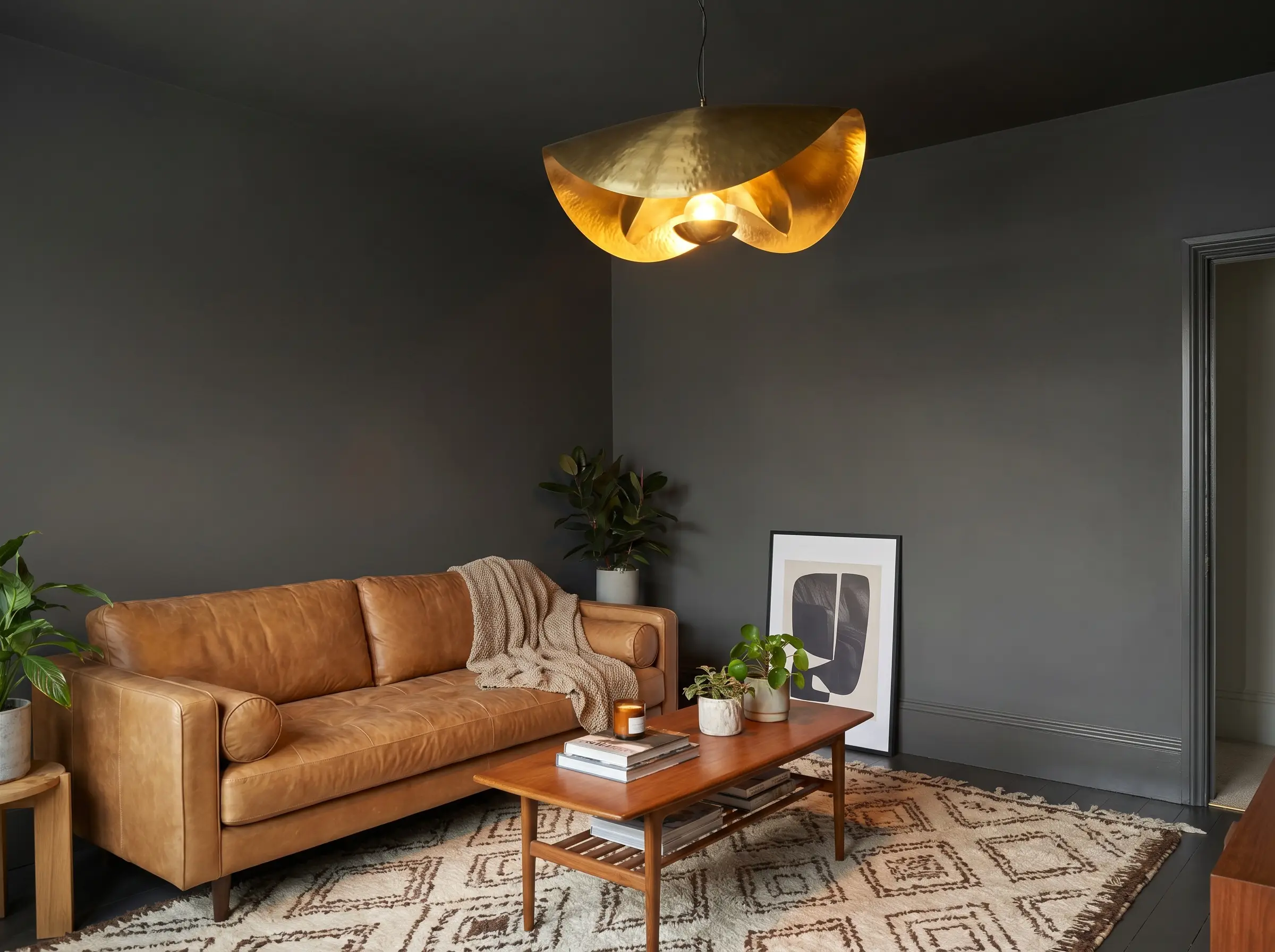 Monolithic Kendall Charcoal paint covers flat stock MDF baseboards and walls, creating a continuous dark plane behind a cognac leather sofa and geometric rug.