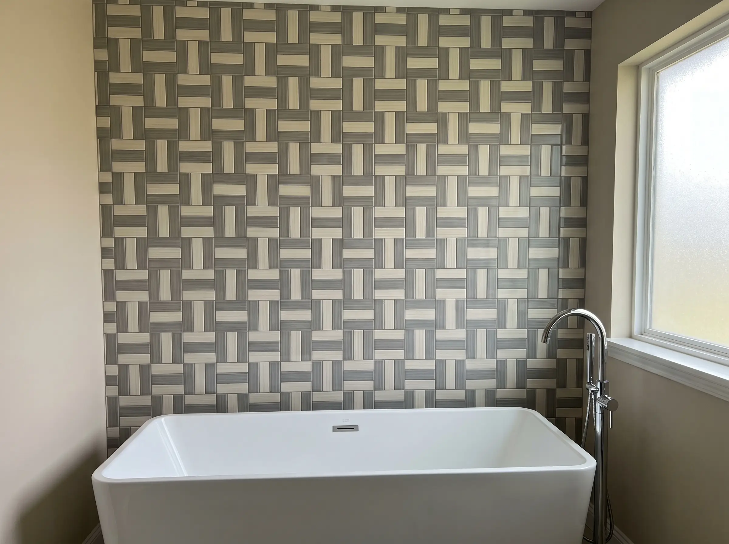 Square ceramic tiles arranged in a crosshatch basketweave pattern create a tactile statement wall behind a sleek white freestanding bathtub and chrome filler.