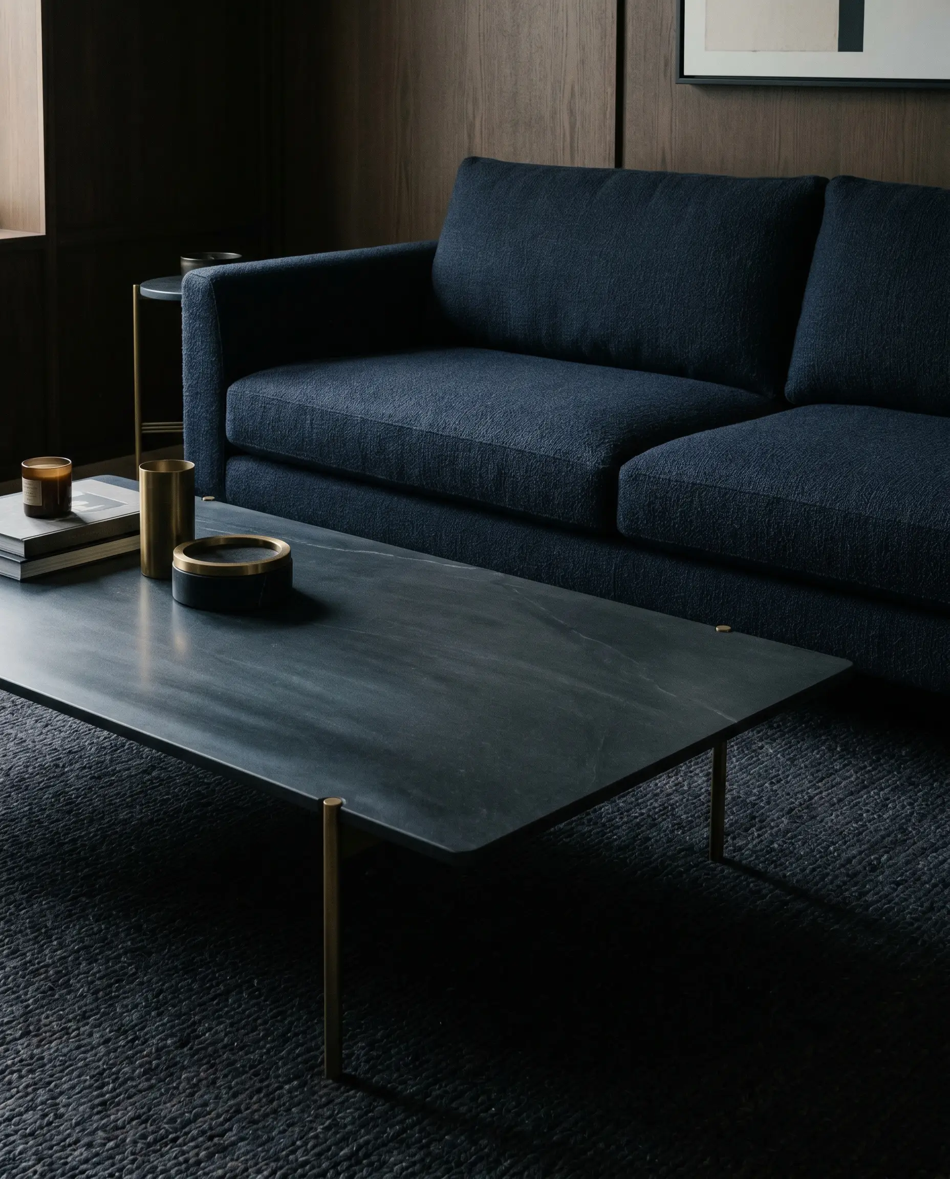 A dark charcoal soapstone coffee table with a matte finish blends seamlessly with the visual weight of a dark navy blue sofa and textured rug.