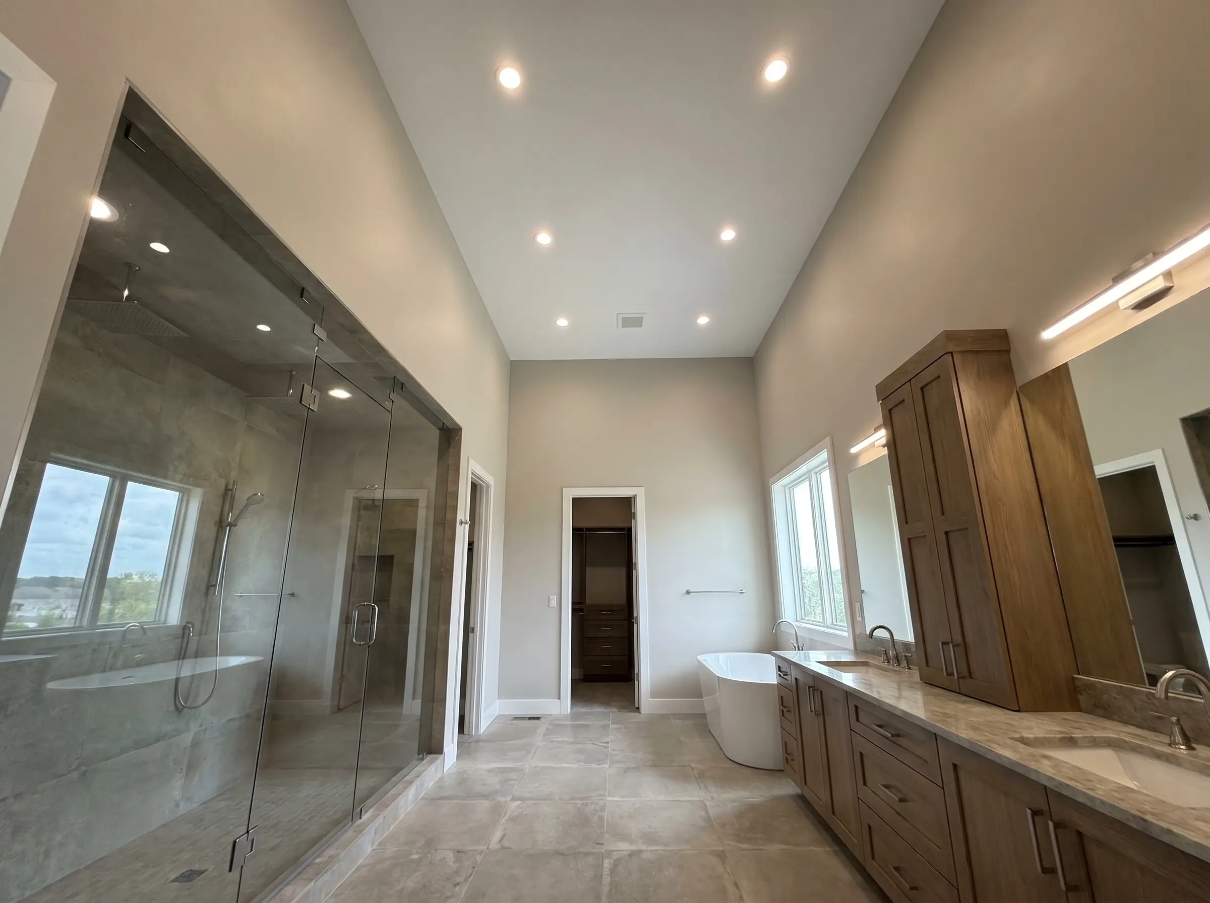 A flawlessly smooth ceiling painted in flat Decorator's White tops a sleek glass shower and wide vanity in this Benjamin Moore Pale Oak bathroom.