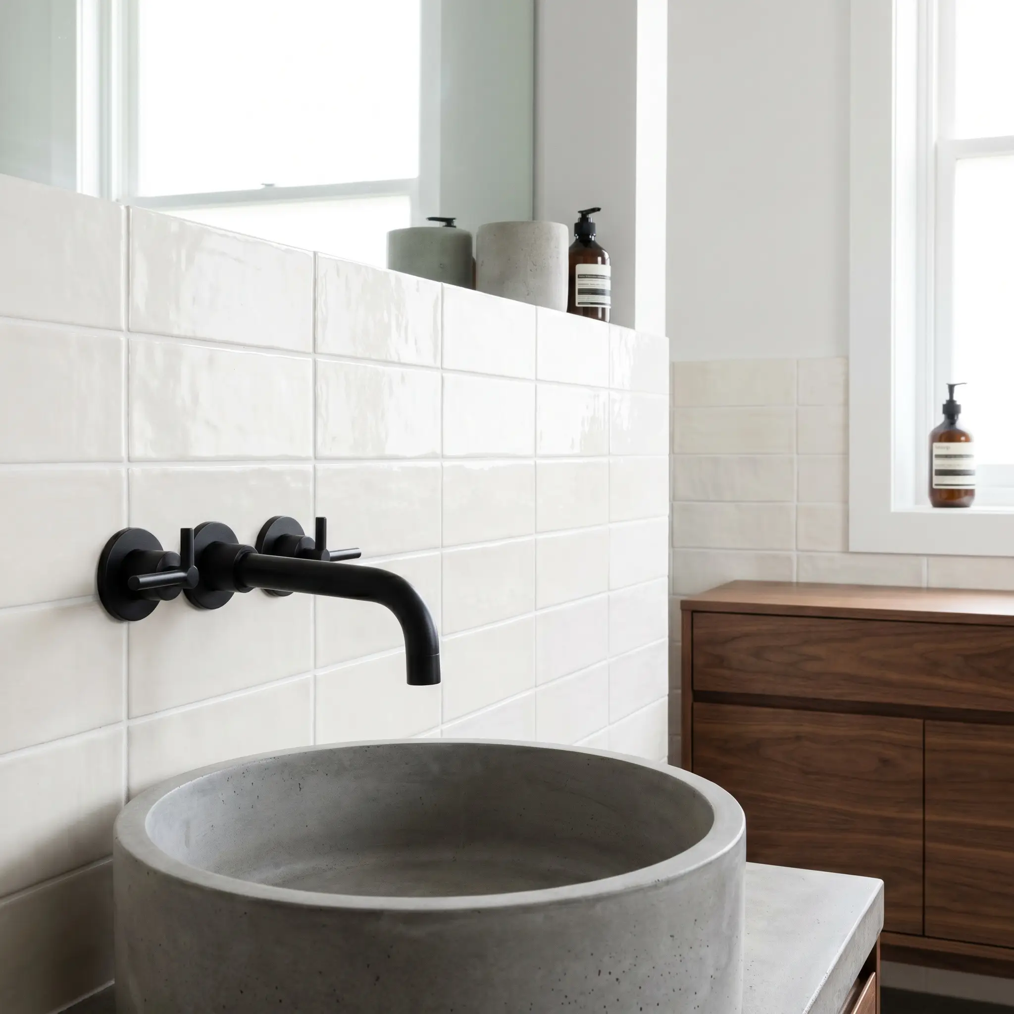 Rectangular ceramic tiles form a double horizontal stack pattern behind a matte black wall-mounted faucet, concrete vessel sink, and stylish walnut vanity.