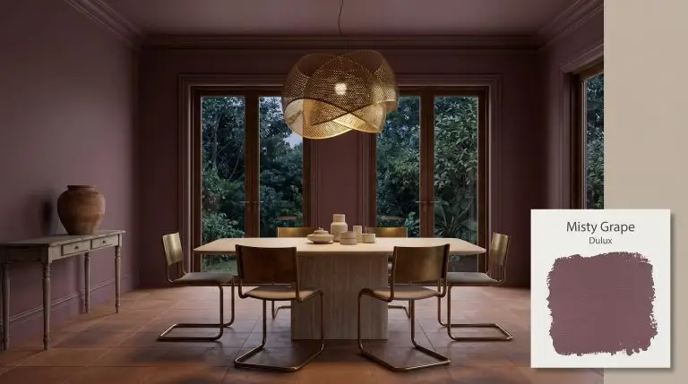 A honed travertine pedestal table and cantilevered chairs sit inside an immersive dining space painted in Dulux Misty Grape (Hex #65424d).