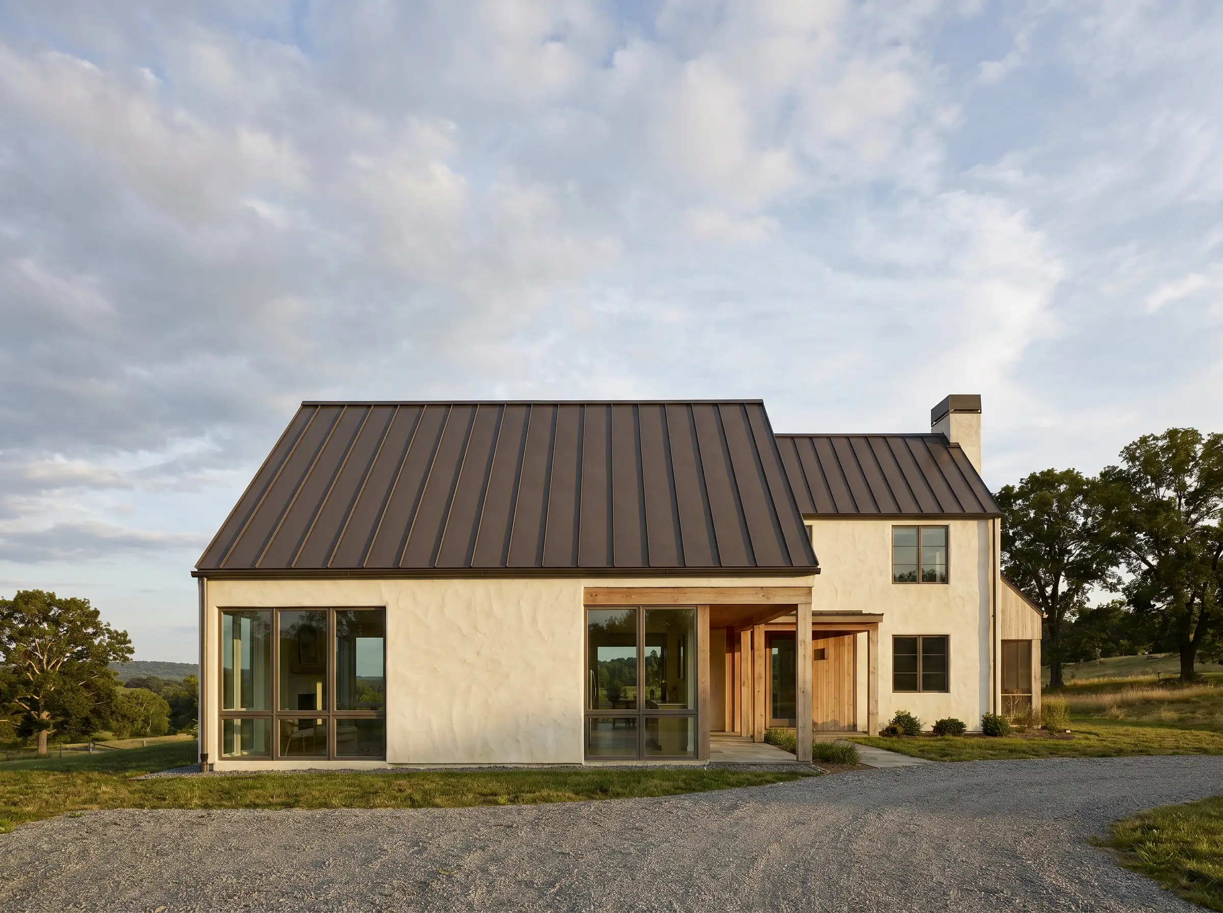 Hand-troweled cream stucco walls sit beneath a dark bronze 24-gauge standing seam metal roof constructed with hidden fasteners.