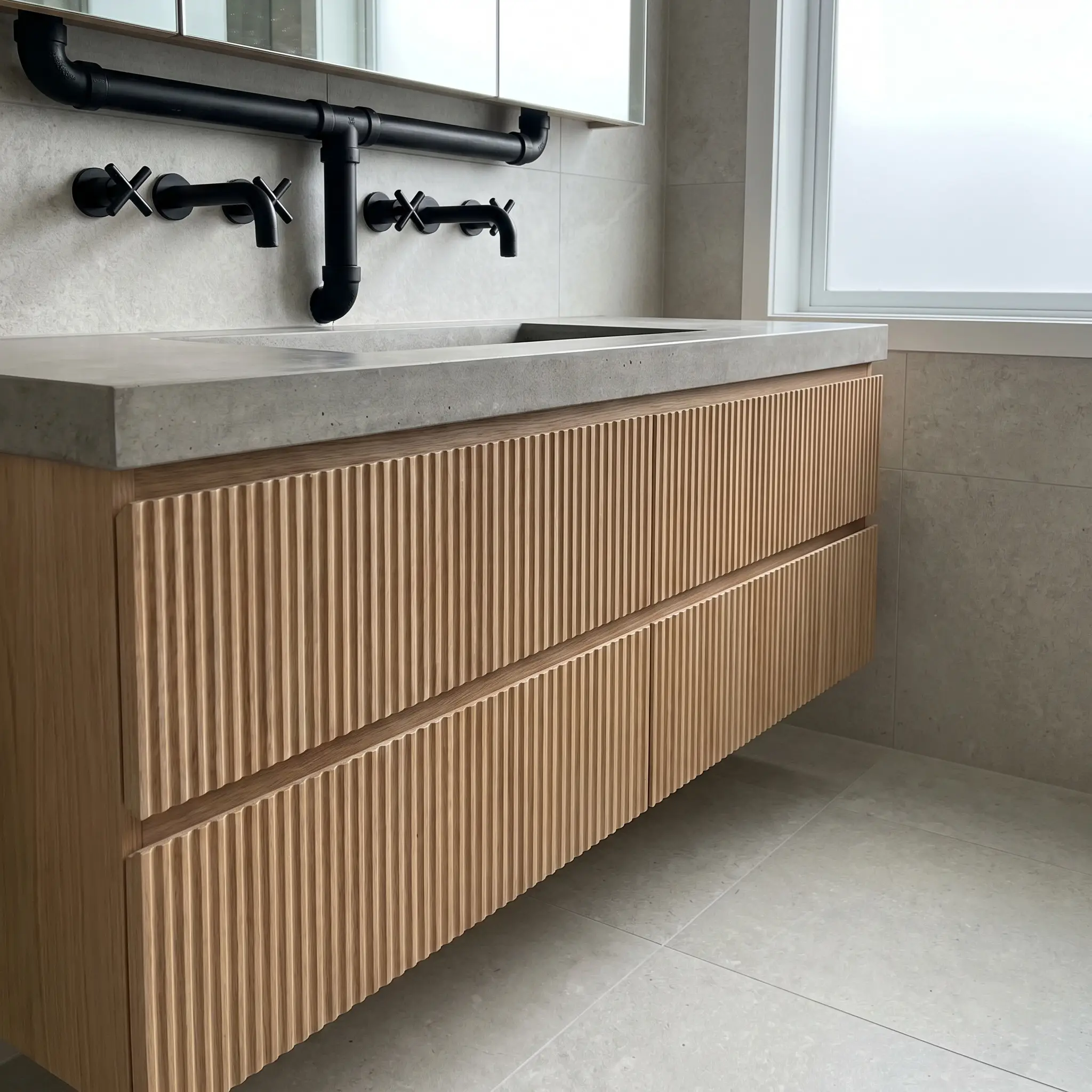 An ultra-minimalist bespoke wood cabinet features hardware-free finger-pull integrated edges with a continuous reverse-bevel that leaves the curved fluted texture entirely uninterrupted.