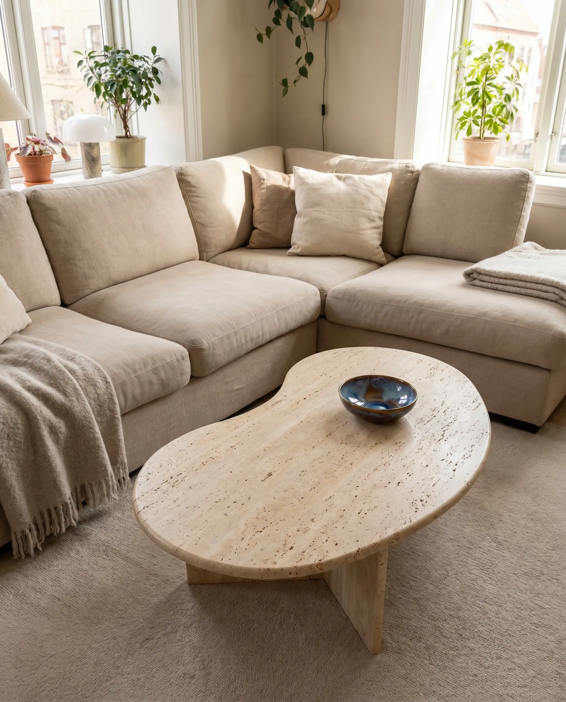 A kidney-shaped honed travertine coffee table for beige sectional seating fits perfectly into the interior corner of an L-shape configuration.