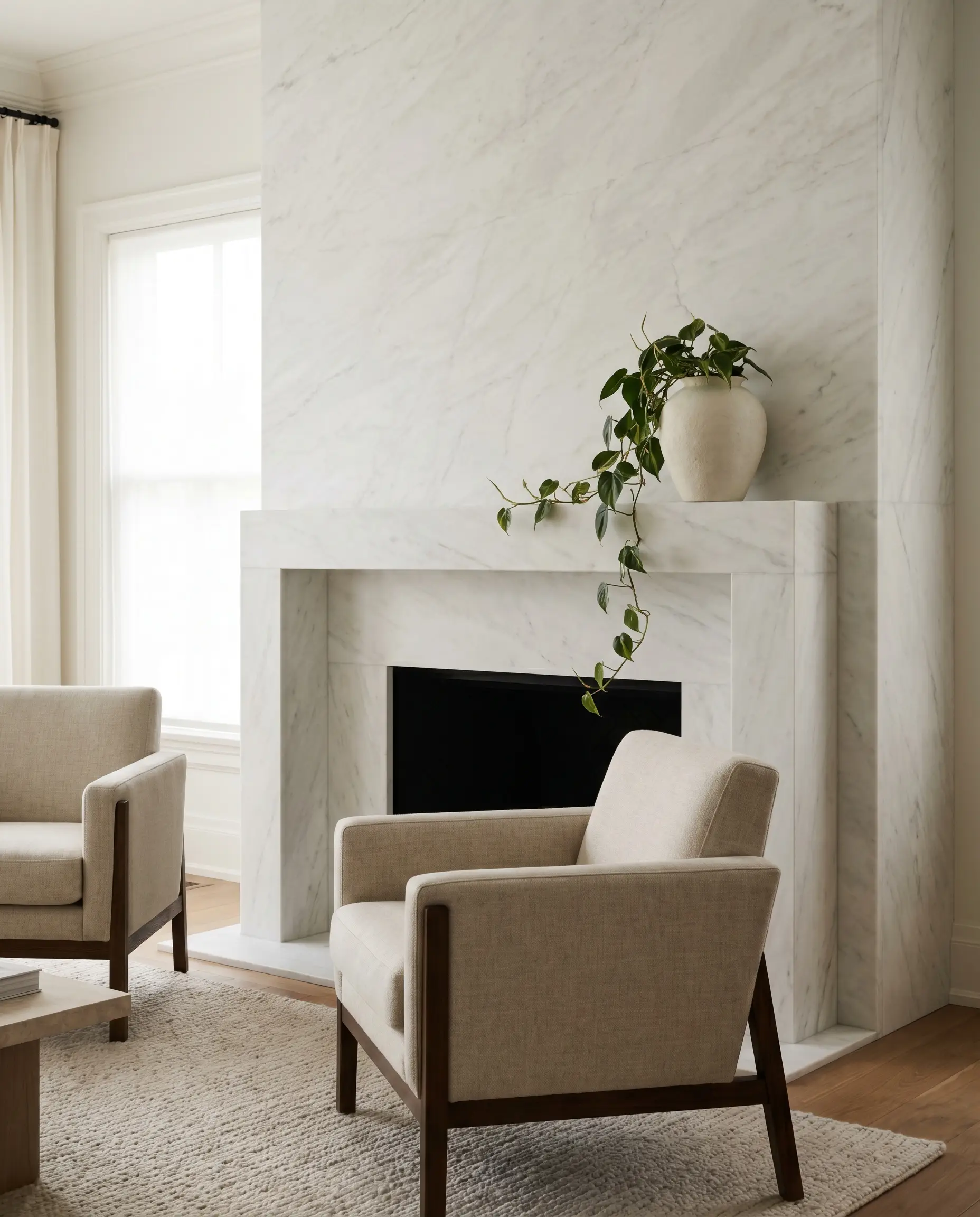 An incredibly dense Imperial Danby stone surround with subtle light grey veining features a minimalist mantel styled with a matte ceramic vessel and trailing green vine.