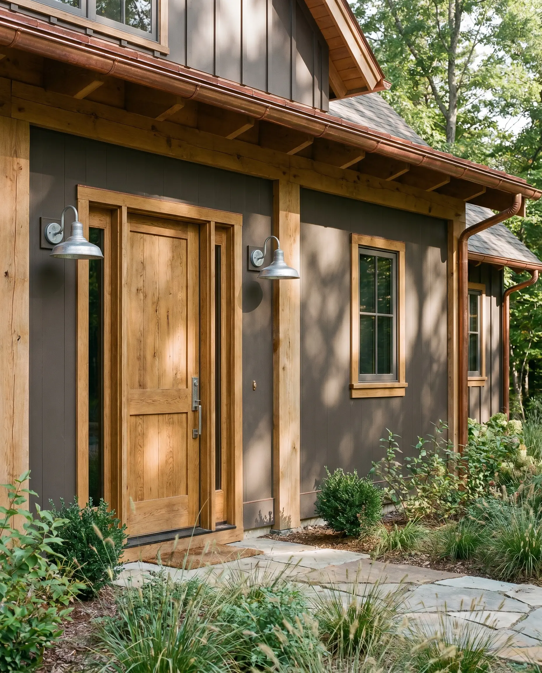 A warm brown-leaning charcoal exterior feature wall harmonizes with natural wood architectural framing, rich copper flashing, and stunning galvanized steel fixtures.