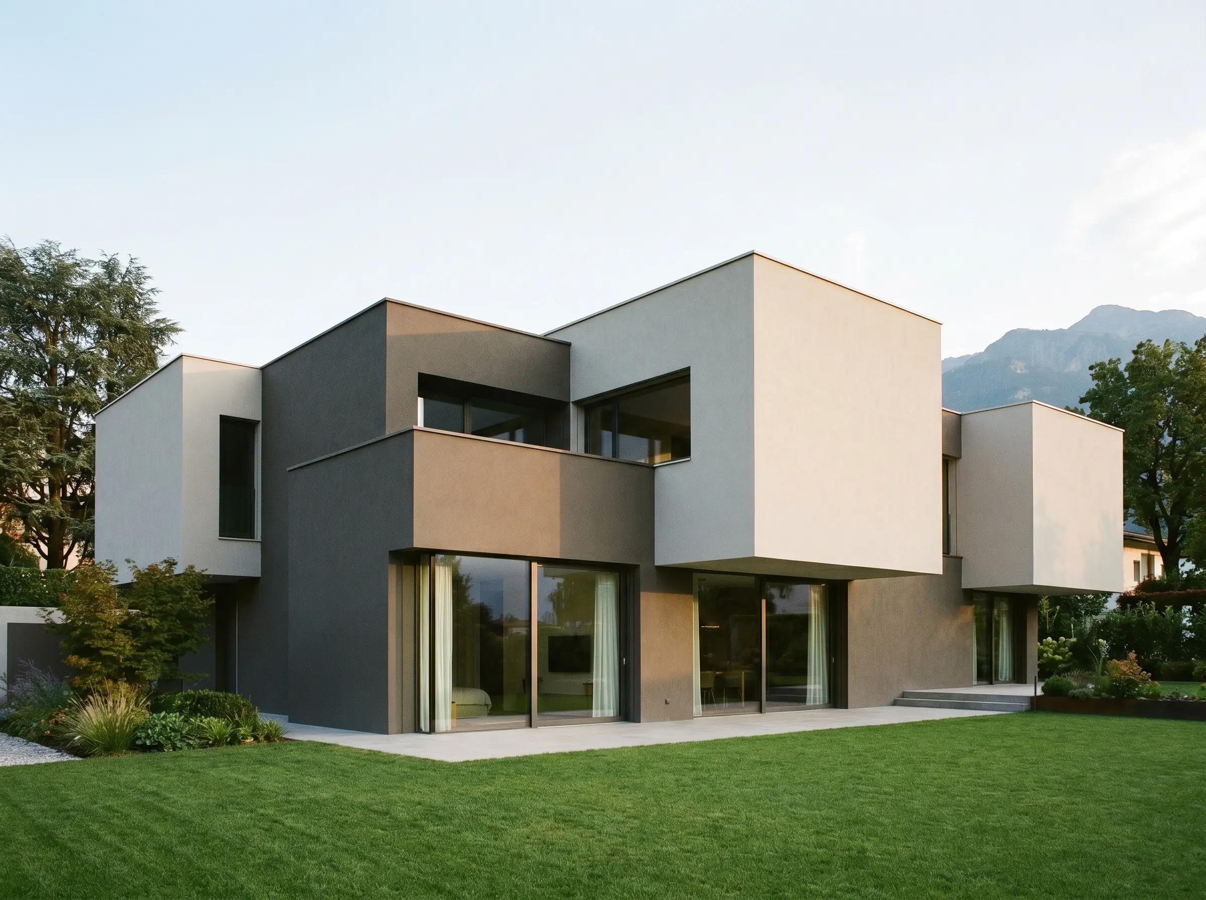 Interlocking structural blocks showcase a heavy dark greige on recessed volumes and a lighter greige on protruding massing above large glass sliding doors.