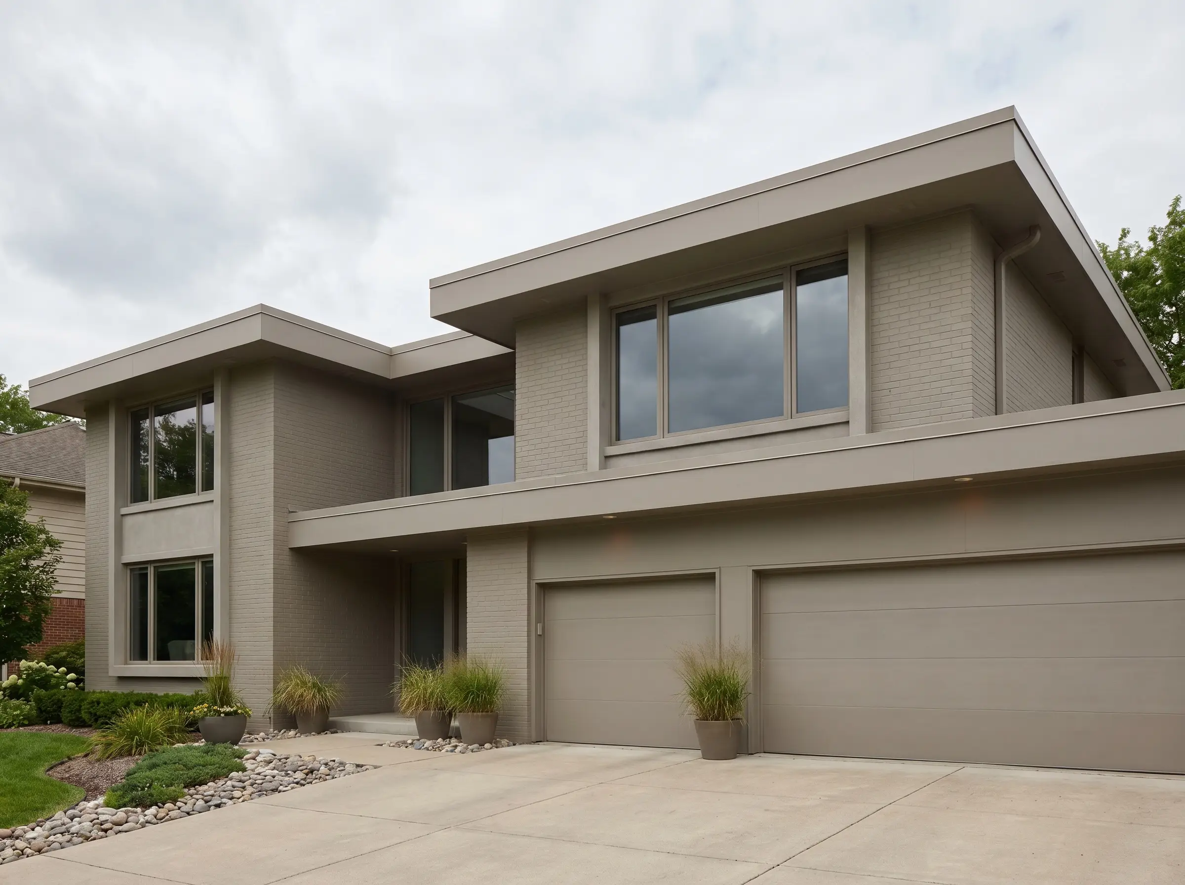 Modern greige facade ideas culminate in a monochromatic wash where masonry siding, architectural trim, and modern garage doors share a single identical greige pigment.
