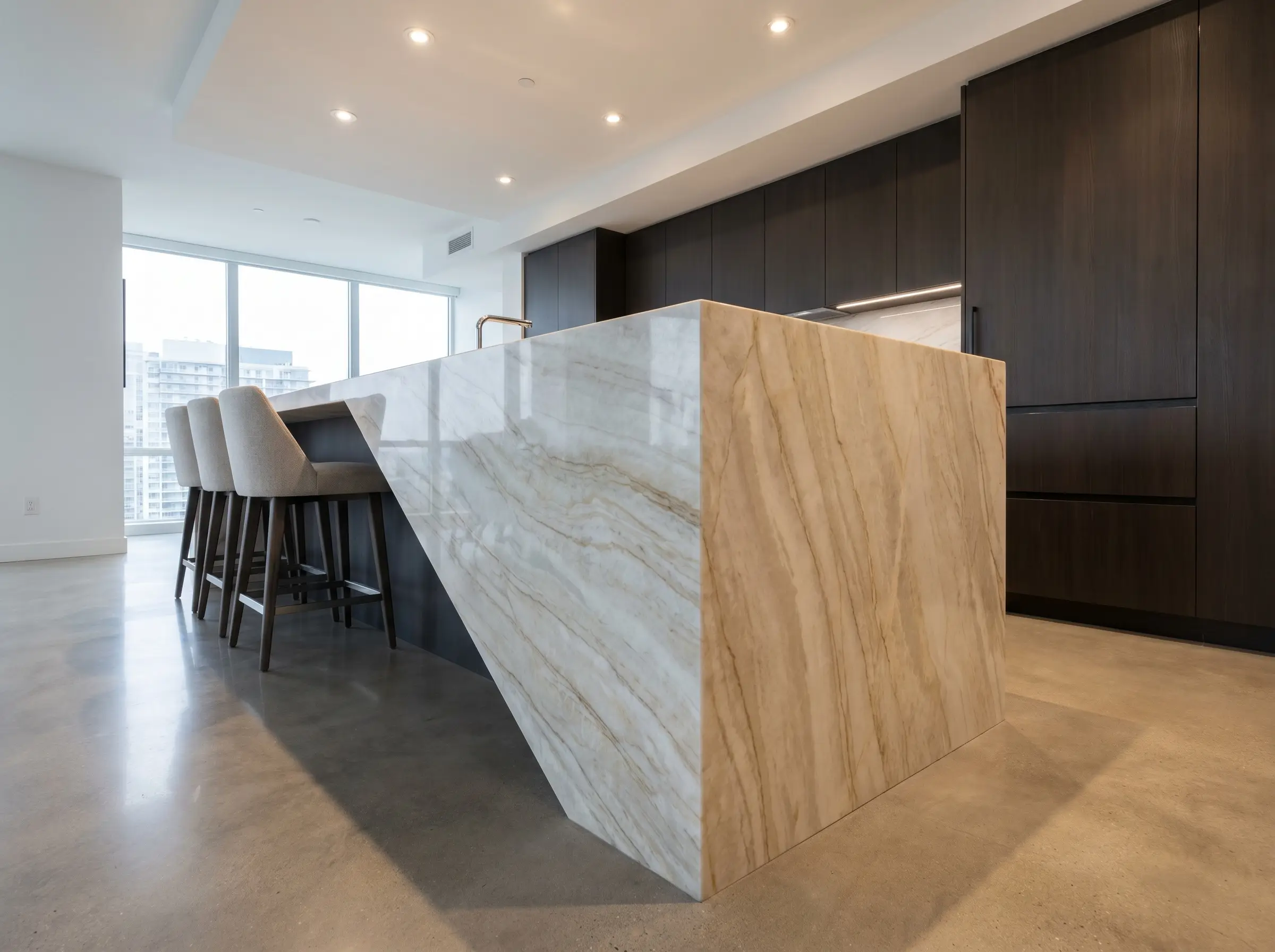 A seamless 45-degree mitered waterfall edge drops to polished concrete floors on these monolithic Taj Mahal quartzite kitchen islands.