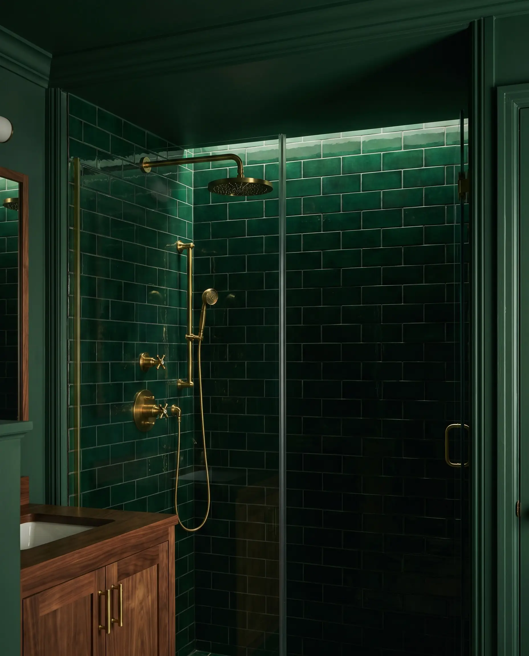 Deep moody Green Smoke ceramic tiles absorb light inside an intimate shower enclosure featuring matching painted ceiling trim and unlacquered brass shower hardware.