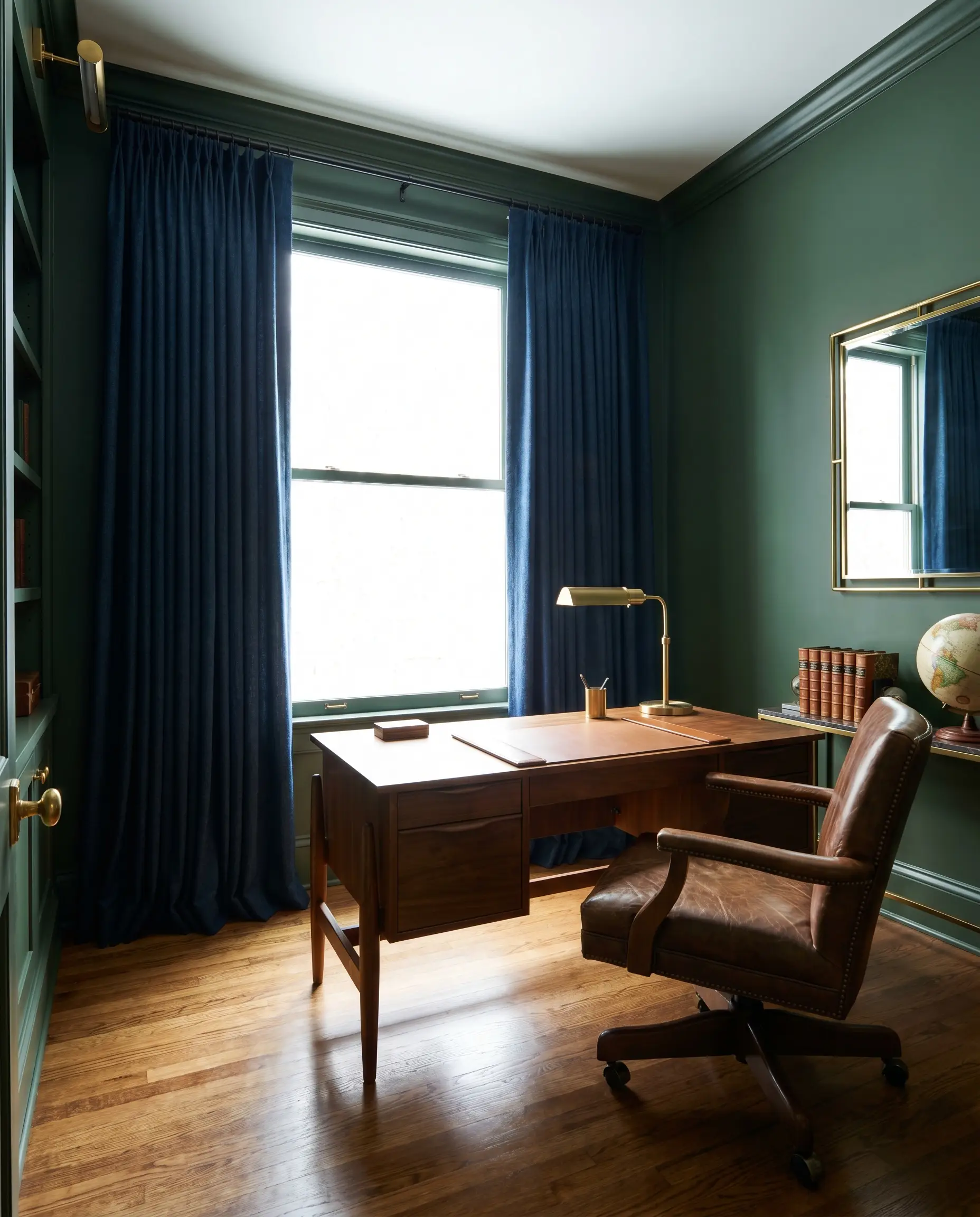 Heavyweight inky navy blue wool curtains anchor a large window behind a mid-range walnut desk and classic leather desk chair.