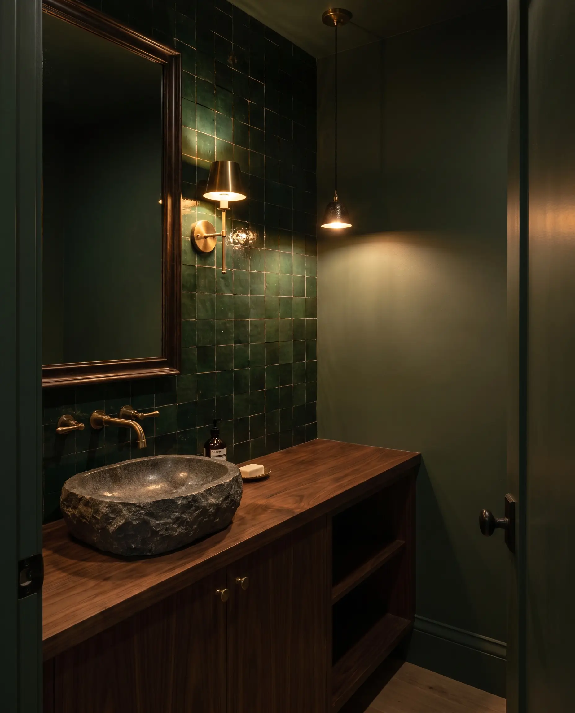 A deep walnut wood vanity sits beneath a floor-to-ceiling green zellige tile bathroom backsplash and walls painted in Sherwin-Williams Pewter Green.