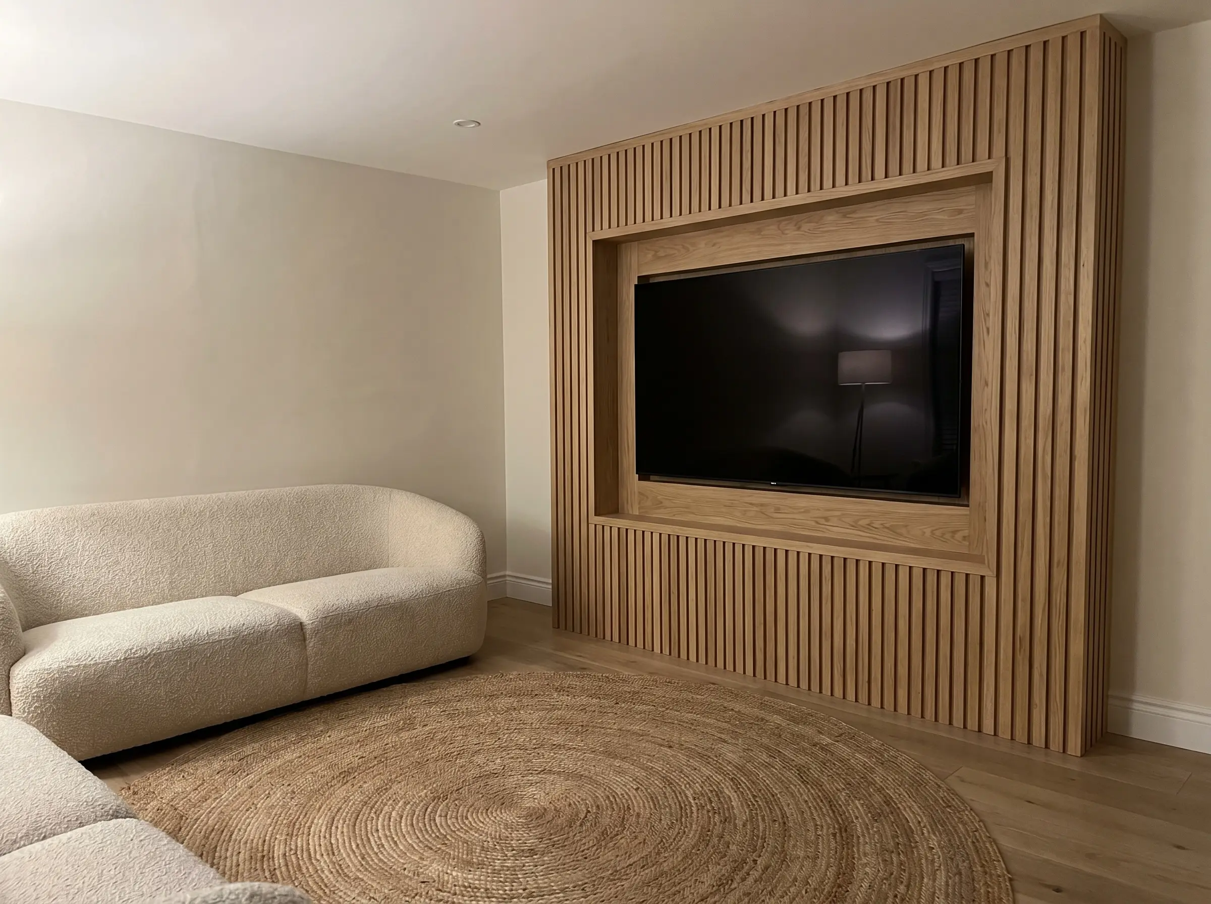 A custom drywall bump-out features a meticulously framed recessed niche housing a television perfectly flush within a wood slat tv wall modern living room.