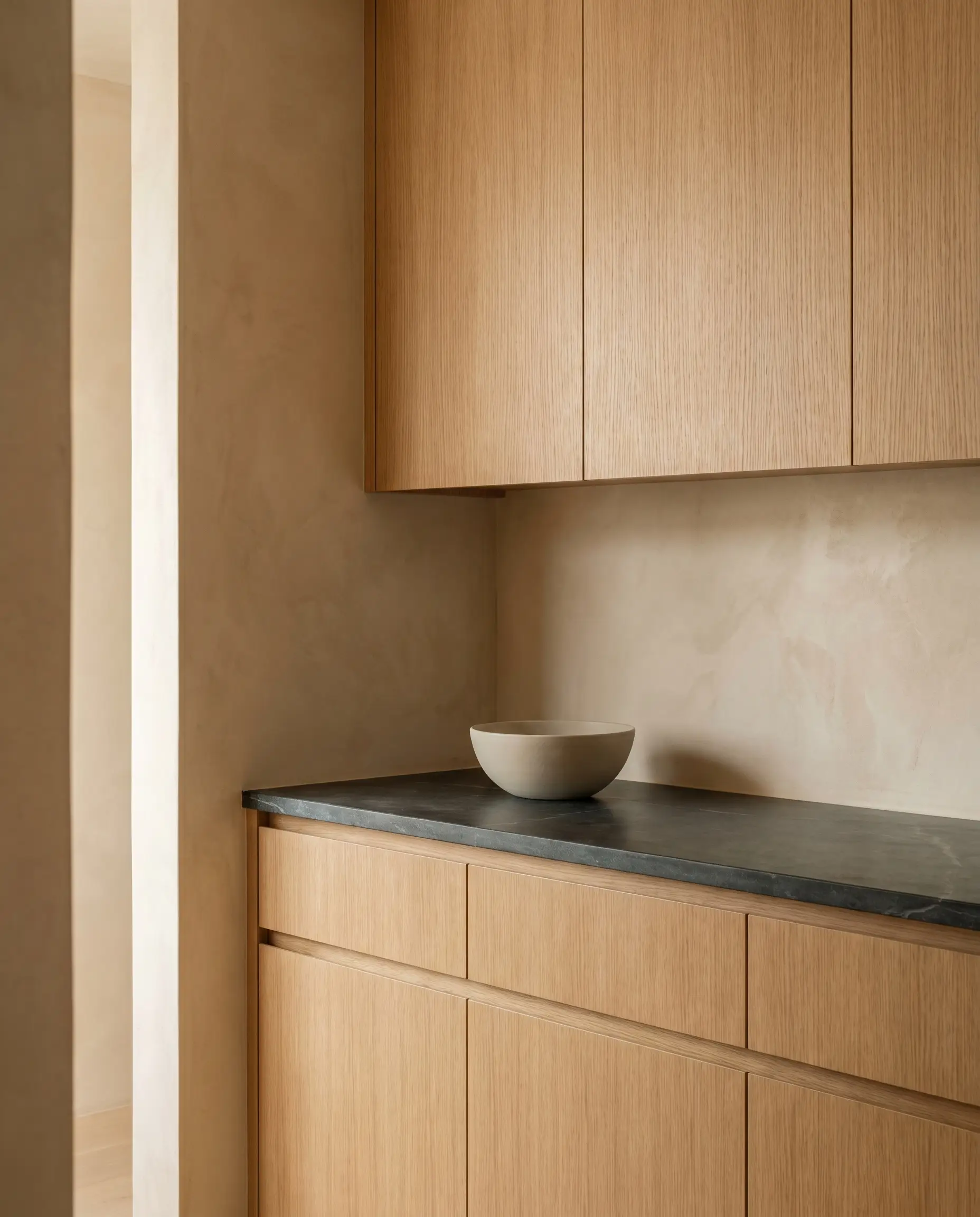 Flat-panel rift-sawn white oak cabinets and a honed soapstone countertop establish the grounding foundation of modern Japandi style kitchens.