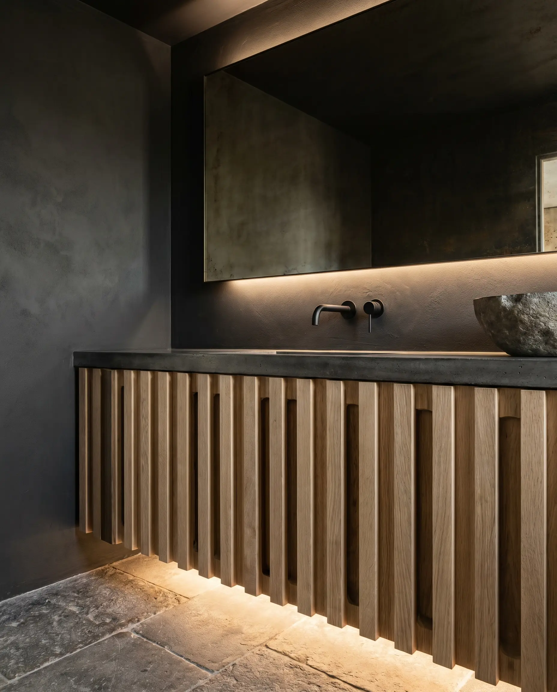 Rigid flat-slat wood paneling with deep rectangular channels forms a geometric base against dark Sherwin-Williams Iron Ore walls and sleek minimalist plumbing fixtures.