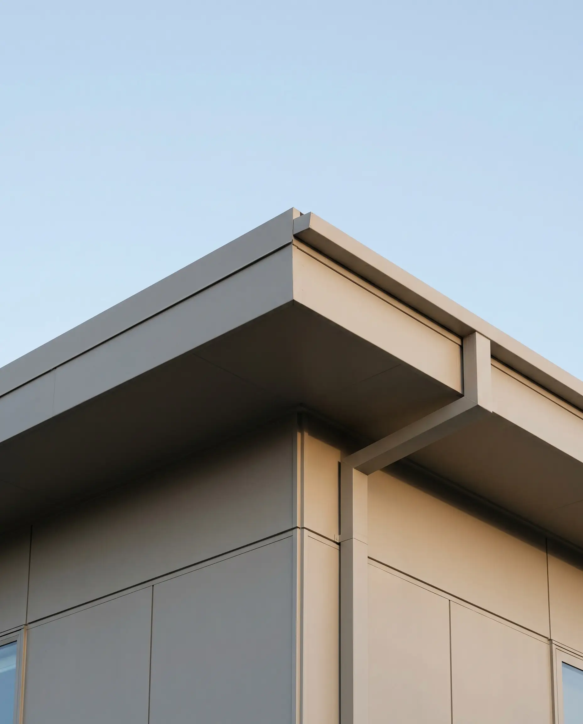 Fascia boards, soffits, and perfectly square integrated gutter systems are painted in the exact same greige shade as the primary exterior siding.