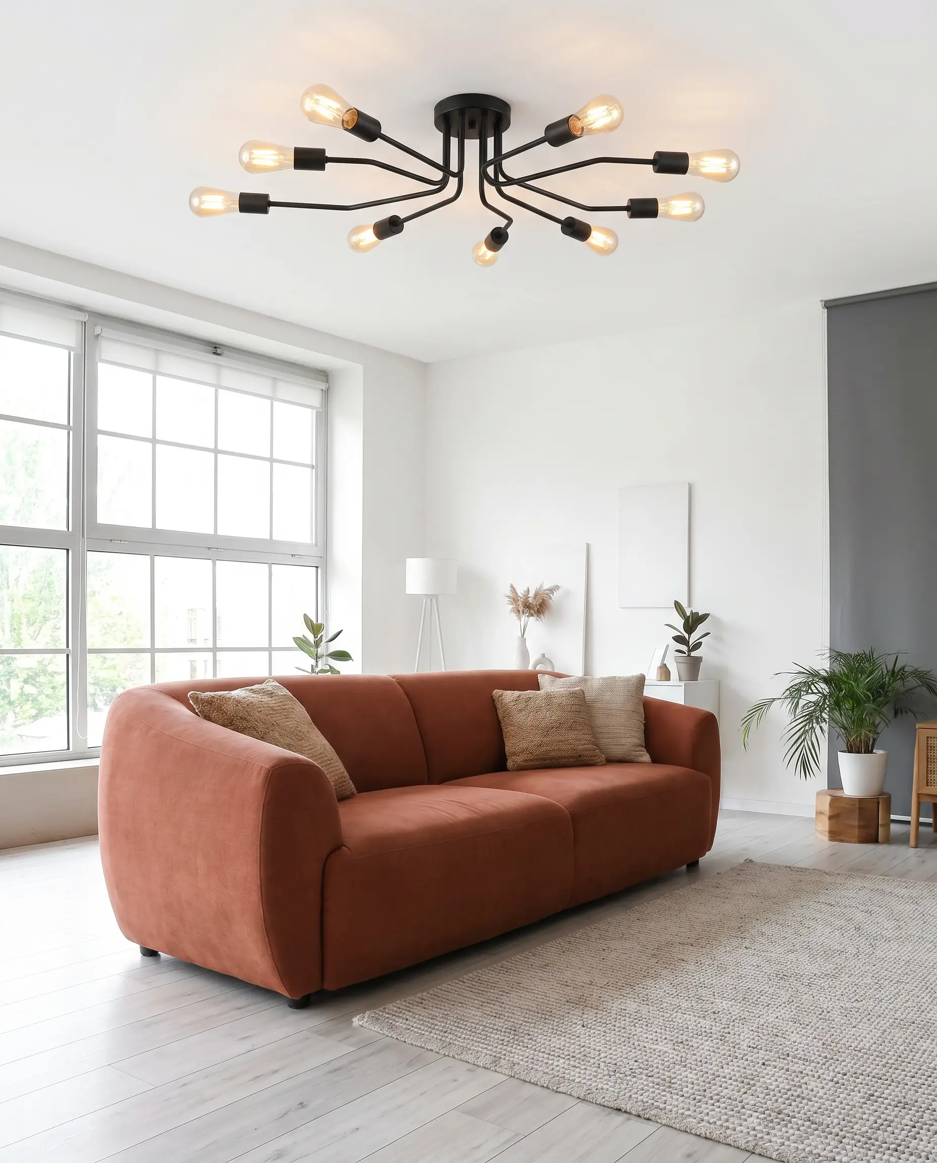 A matte black powder-coated steel multi-arm semi-flush mount spans a white ceiling above a contemporary living space featuring a terracotta-toned sofa and ash wood flooring.