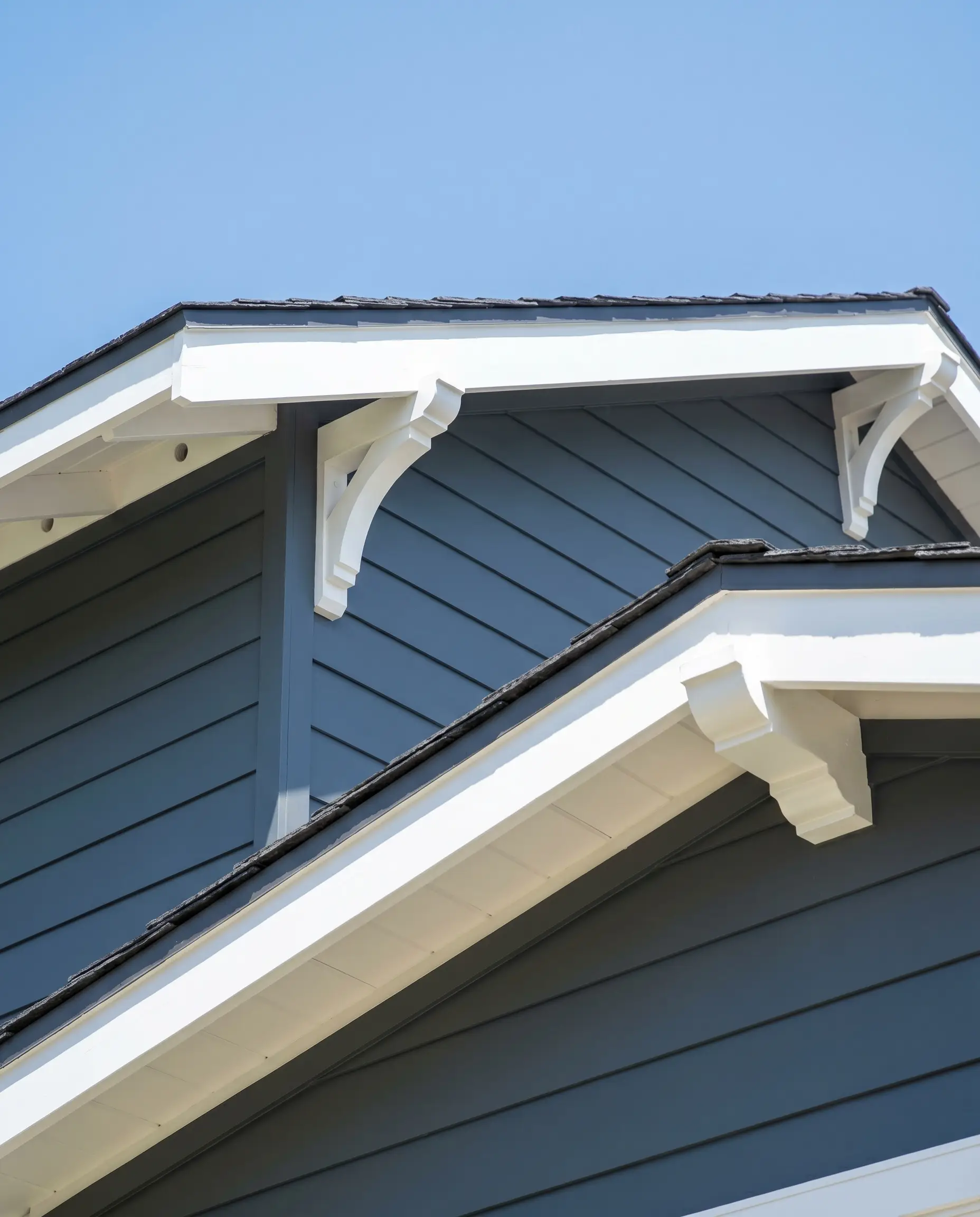 A deeply saturated, stormy blue-gray exterior wall highlights exposed structural skeleton details, featuring freshly painted, crisp white rafter tails and decorative corbels.