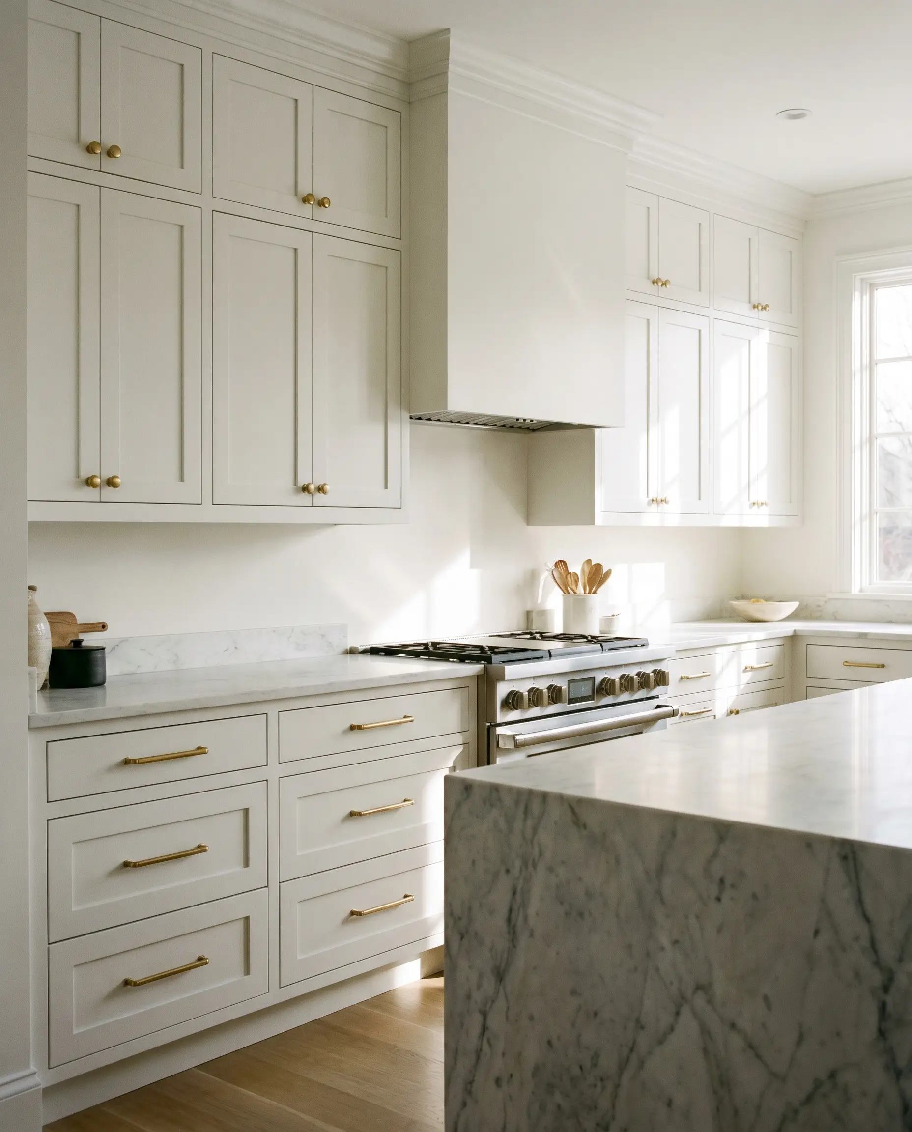 Solid brass round knobs mount exclusively on upper shaker doors while horizontal brass bar pulls line the lower shaker drawers in a crisp white kitchen.