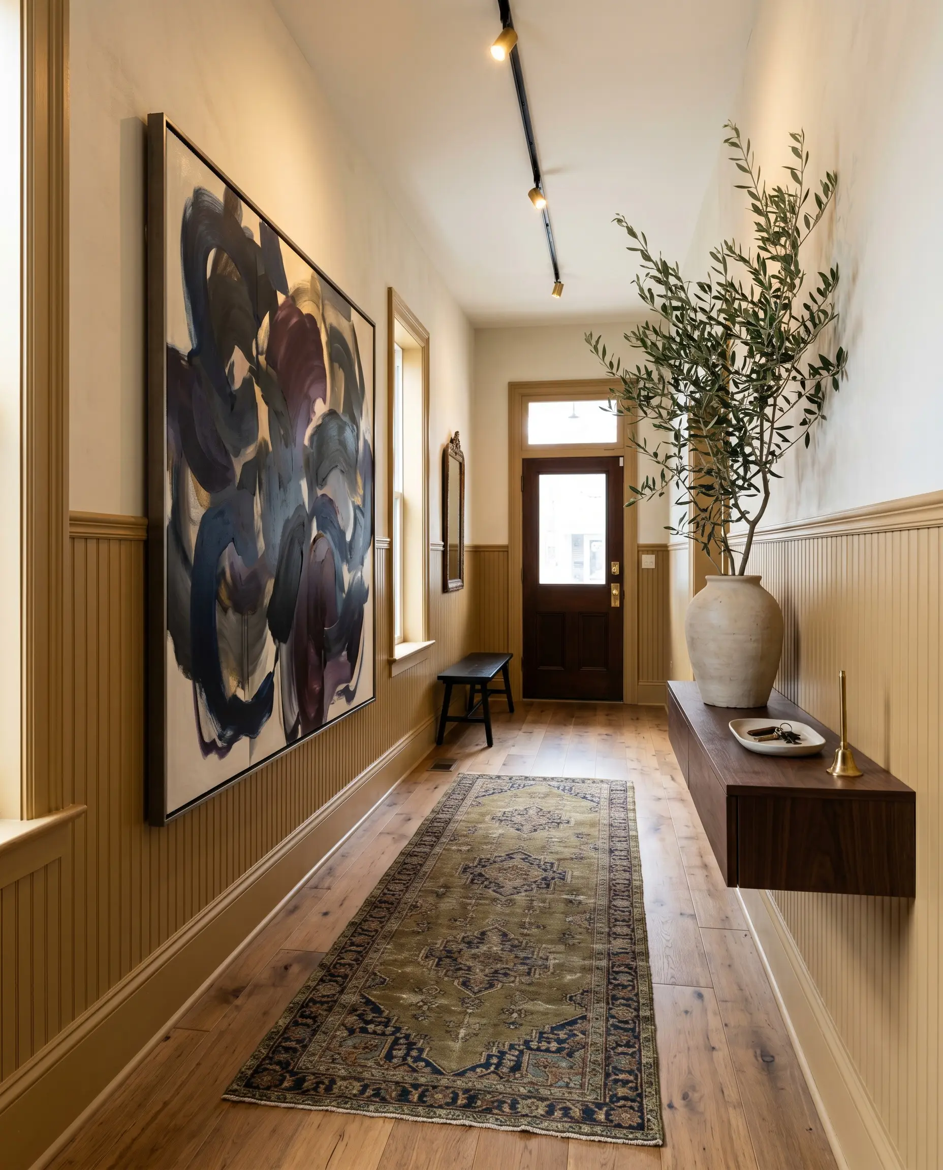 Tall earthy beadboard wainscoting supports a large navy and aubergine abstract canvas above an antique Persian runner and a floating console table holding botanical branches.