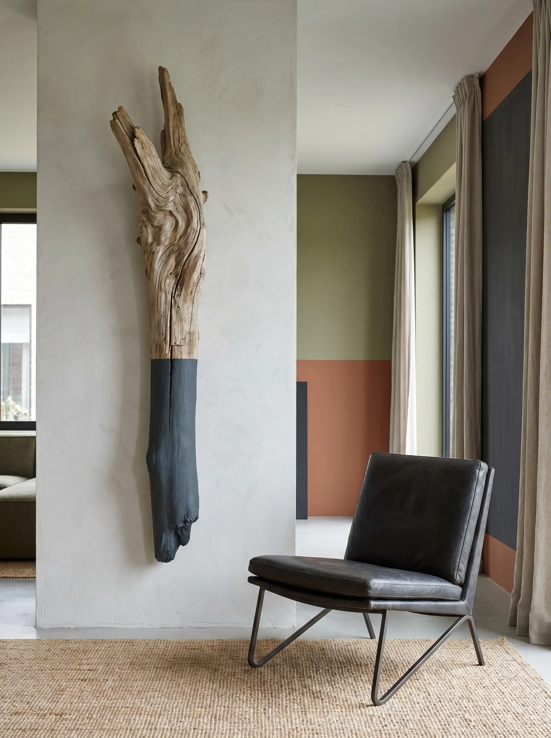 A vertical driftwood branch featuring a razor-sharp Farrow & Ball Down Pipe chalk paint color block stands beside a sleek modern reading chair.