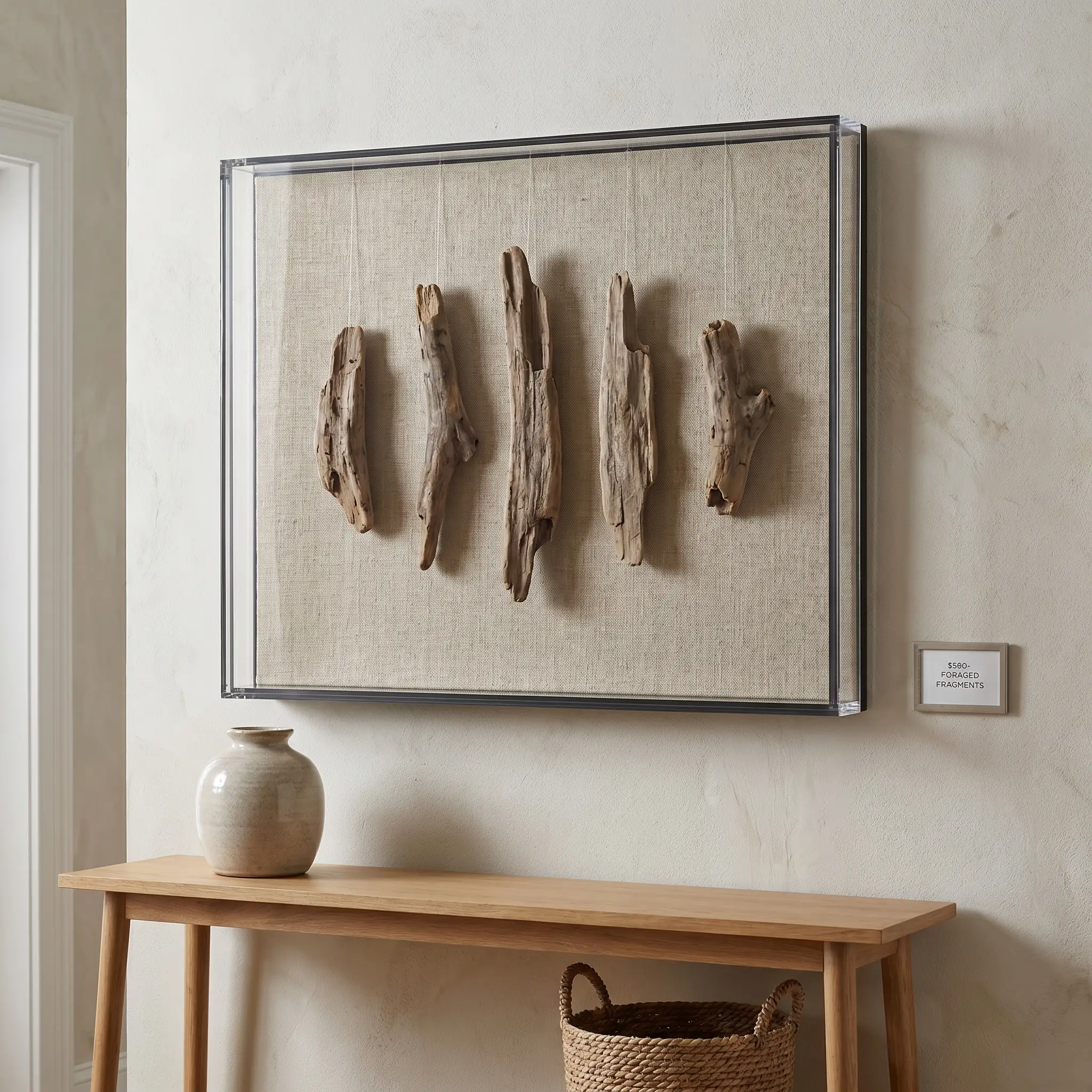 Small textured driftwood shards float invisibly inside a raw linen-backed shadow box framing mounted above a sleek entryway console.