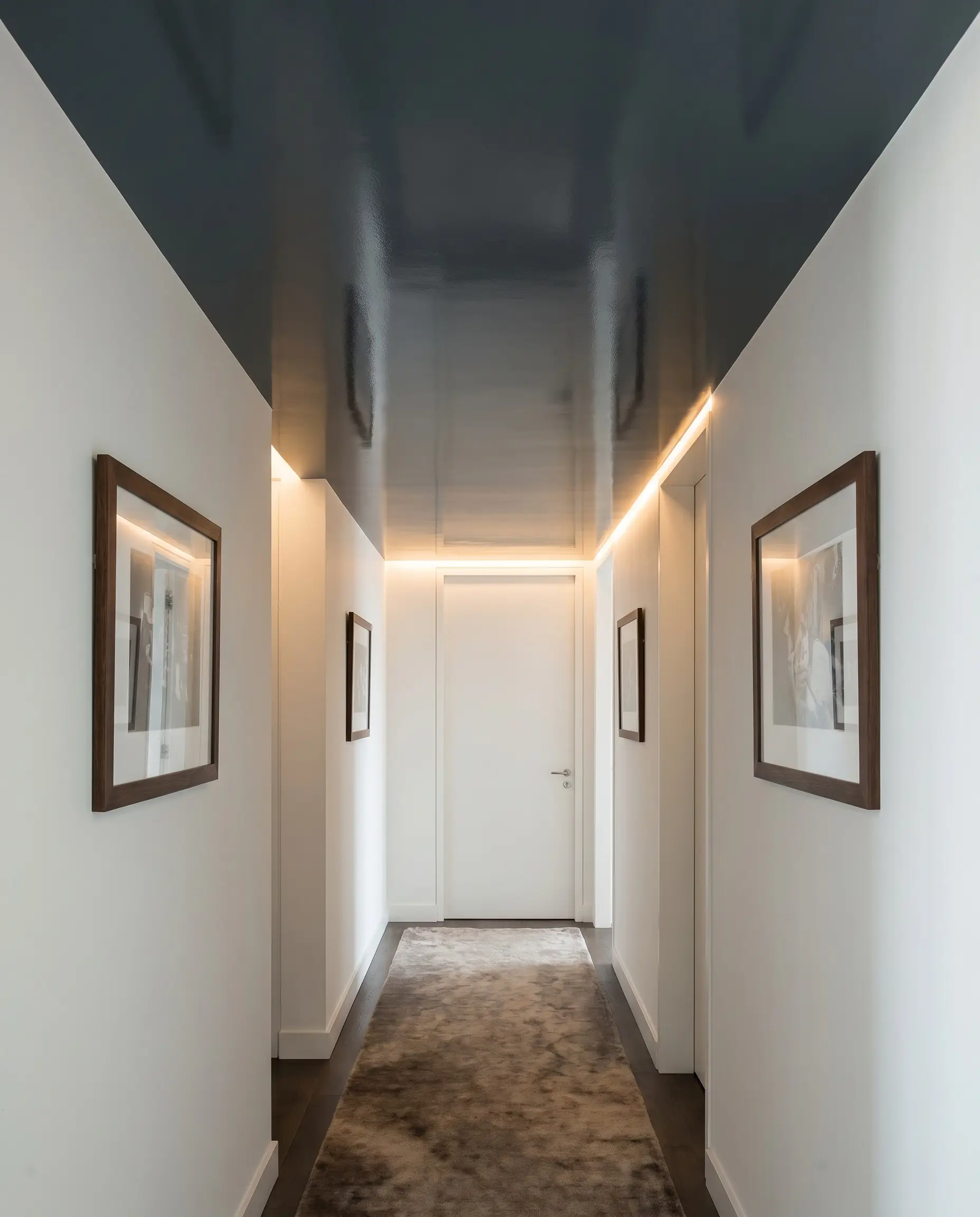 A highly reflective Farrow & Ball Hague Blue lacquered ceiling contrasts against soft matte white side walls in this bespoke corridor.