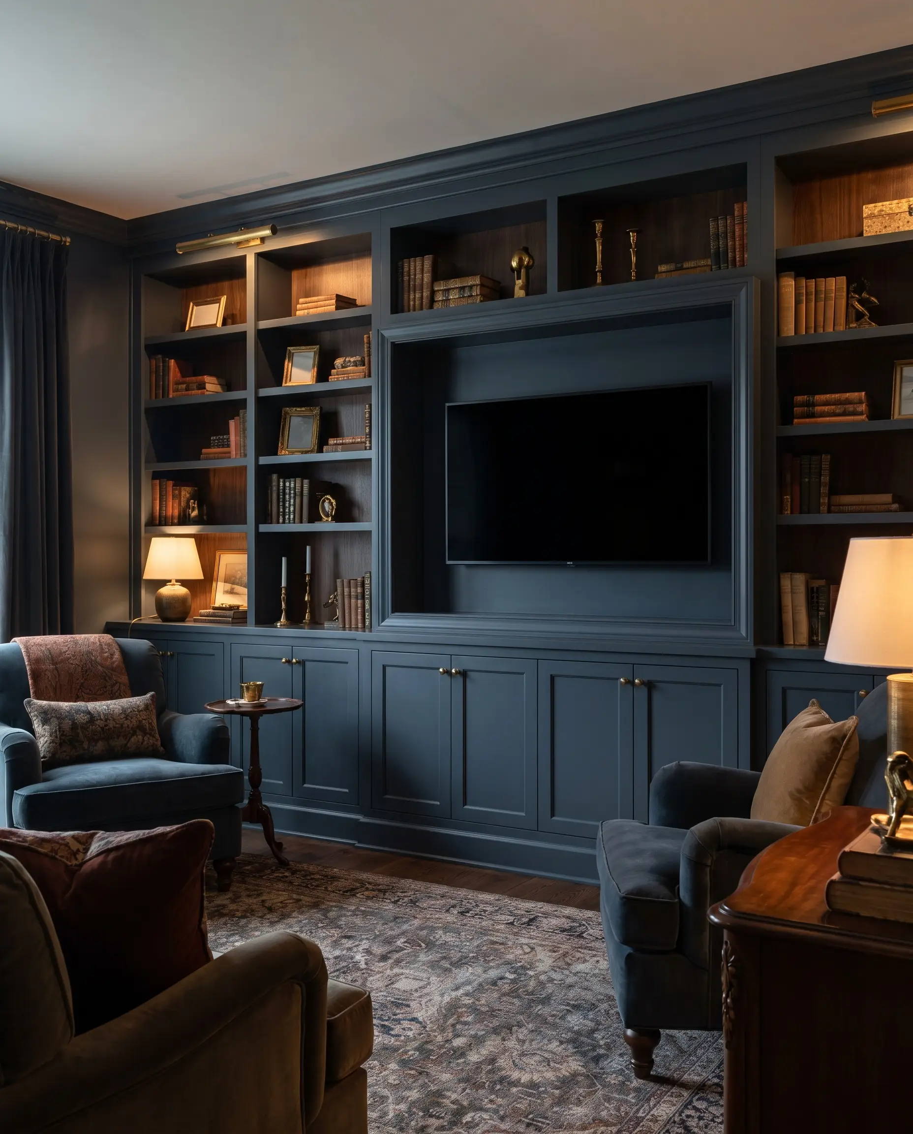 Continuous built-in shelving, base cabinets, and a recessed media box are color-drenched in Farrow and Ball Hague Blue eggshell paint, styled with brass accents.