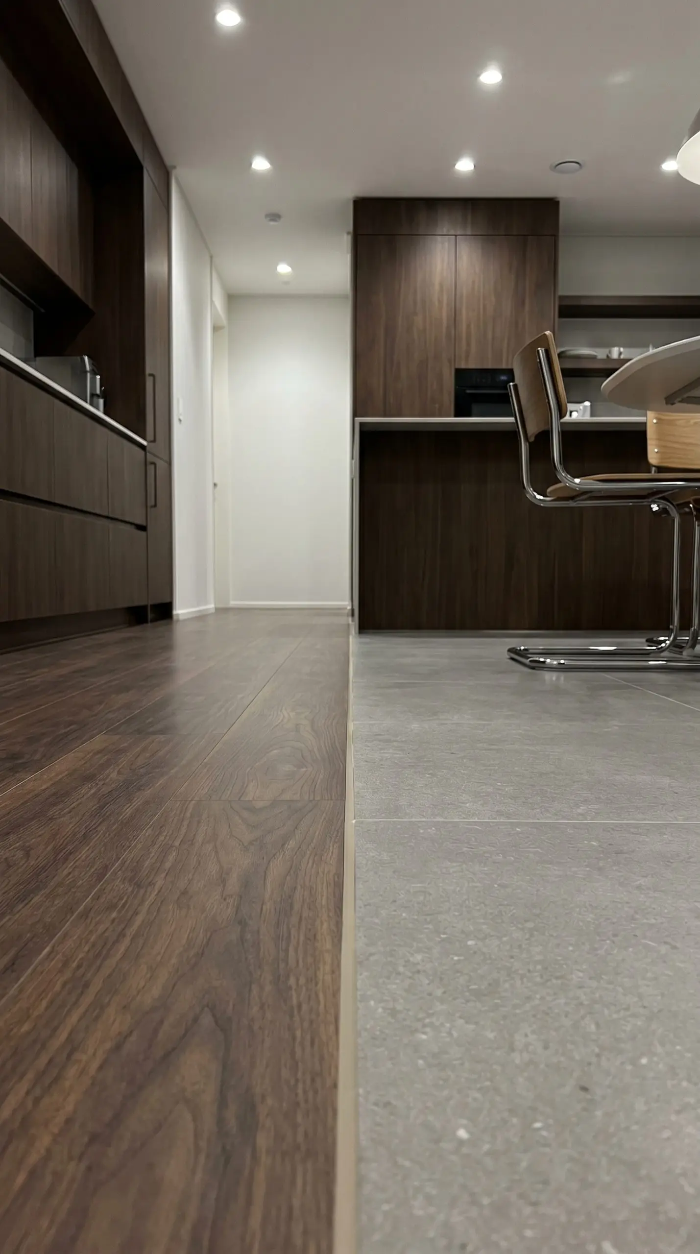A highly controlled 1/8-inch gap filled with sanded acrylic caulk matches the tile grout between luxury vinyl plank and large-format porcelain tile.