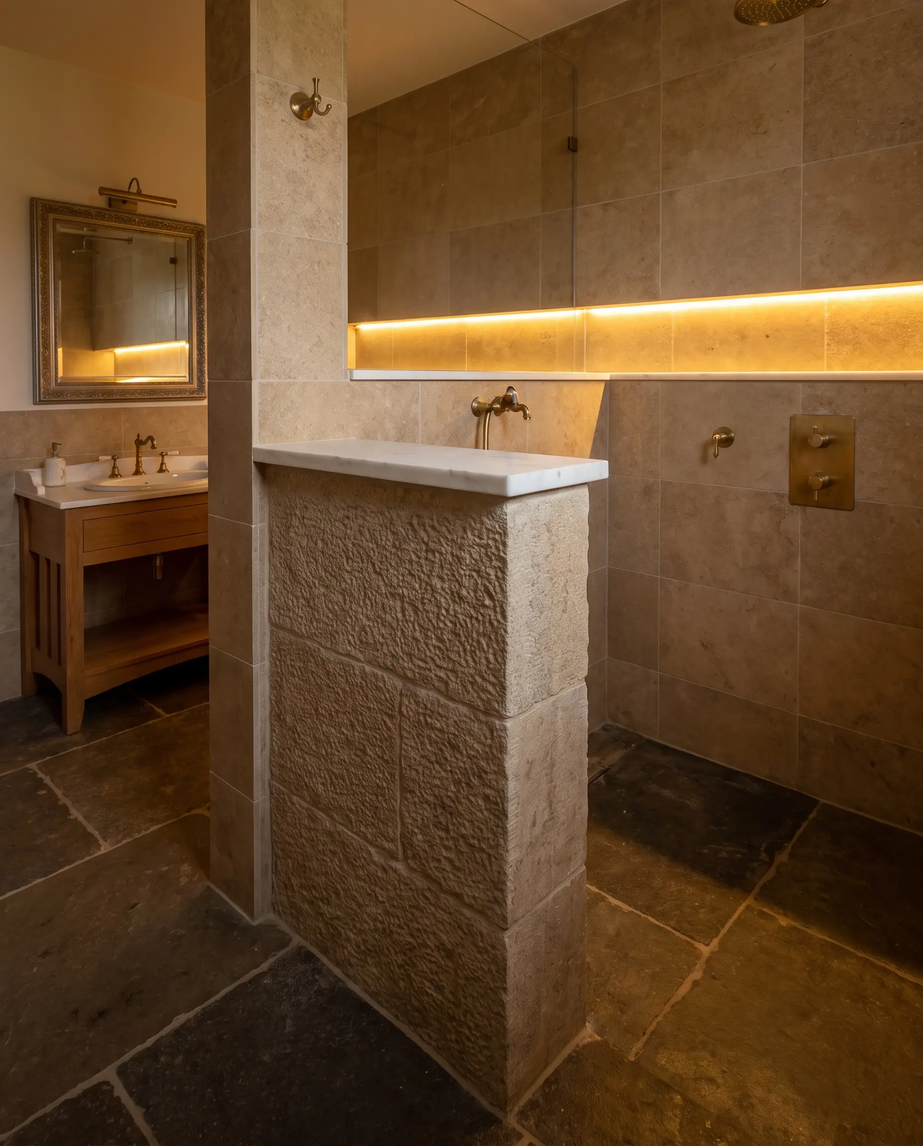 A heavy masonry pony wall capped with a solid slab of pristine white quartzite physically anchors a traditional doorless walk-in shower beside a classic vanity.