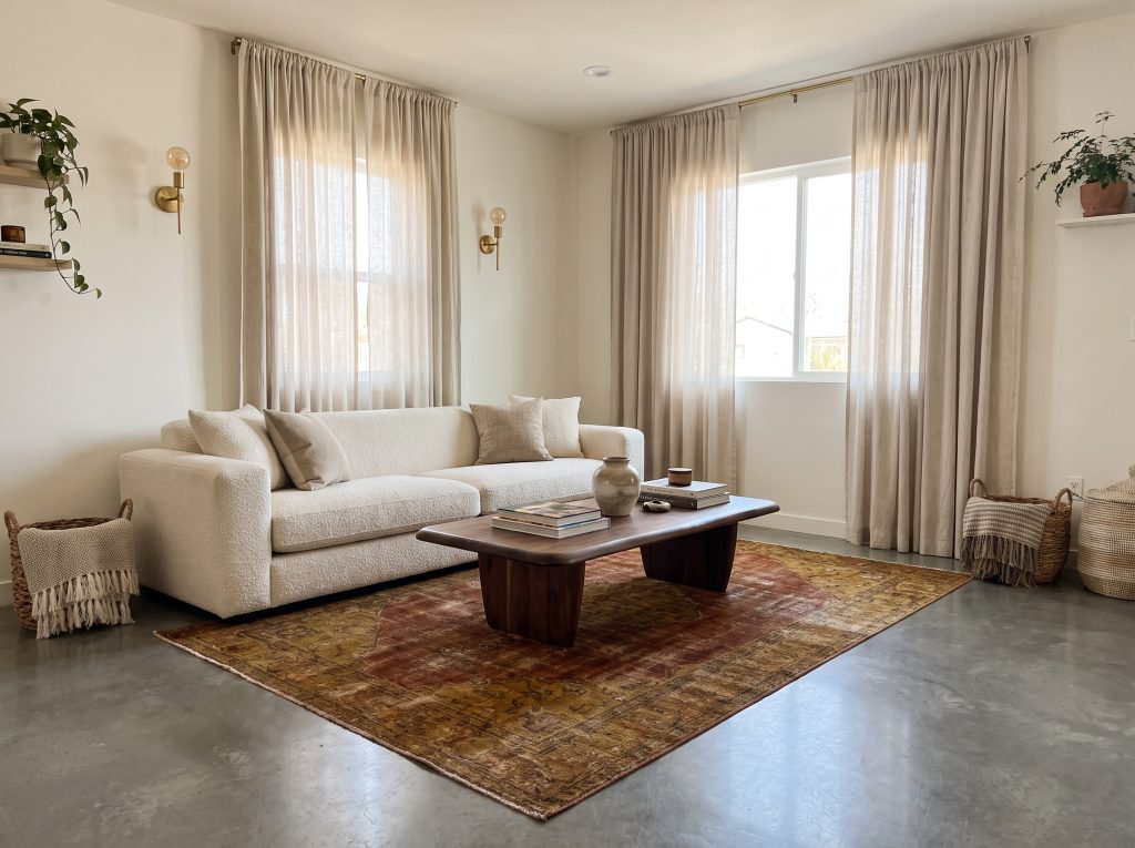 A plush cream boucle sofa and walnut mid-century coffee table sit on sleek gray flooring in a modern living room.