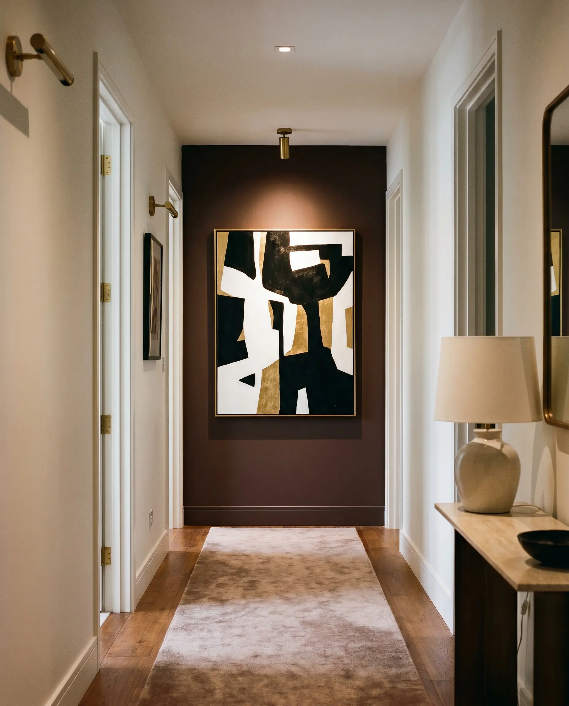 A Sherwin-Williams Carnelian painted terminus wall visually shortens the corridor, anchoring a high-contrast abstract art piece between neutral off-white side walls.