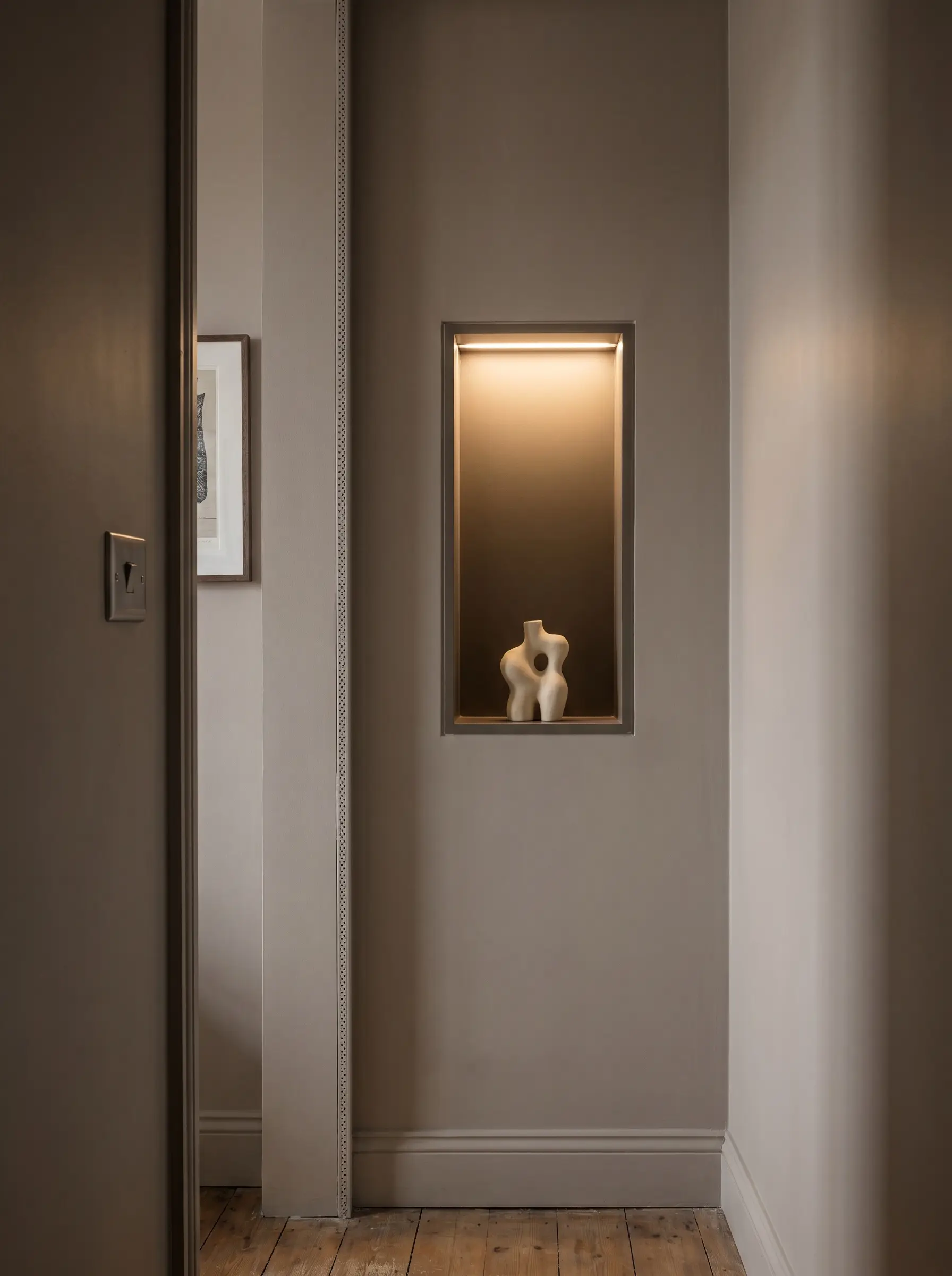 A shallow architectural niche cut directly between the drywall studs houses an elegant ceramic sculpture illuminated by a hidden micro-LED puck light.