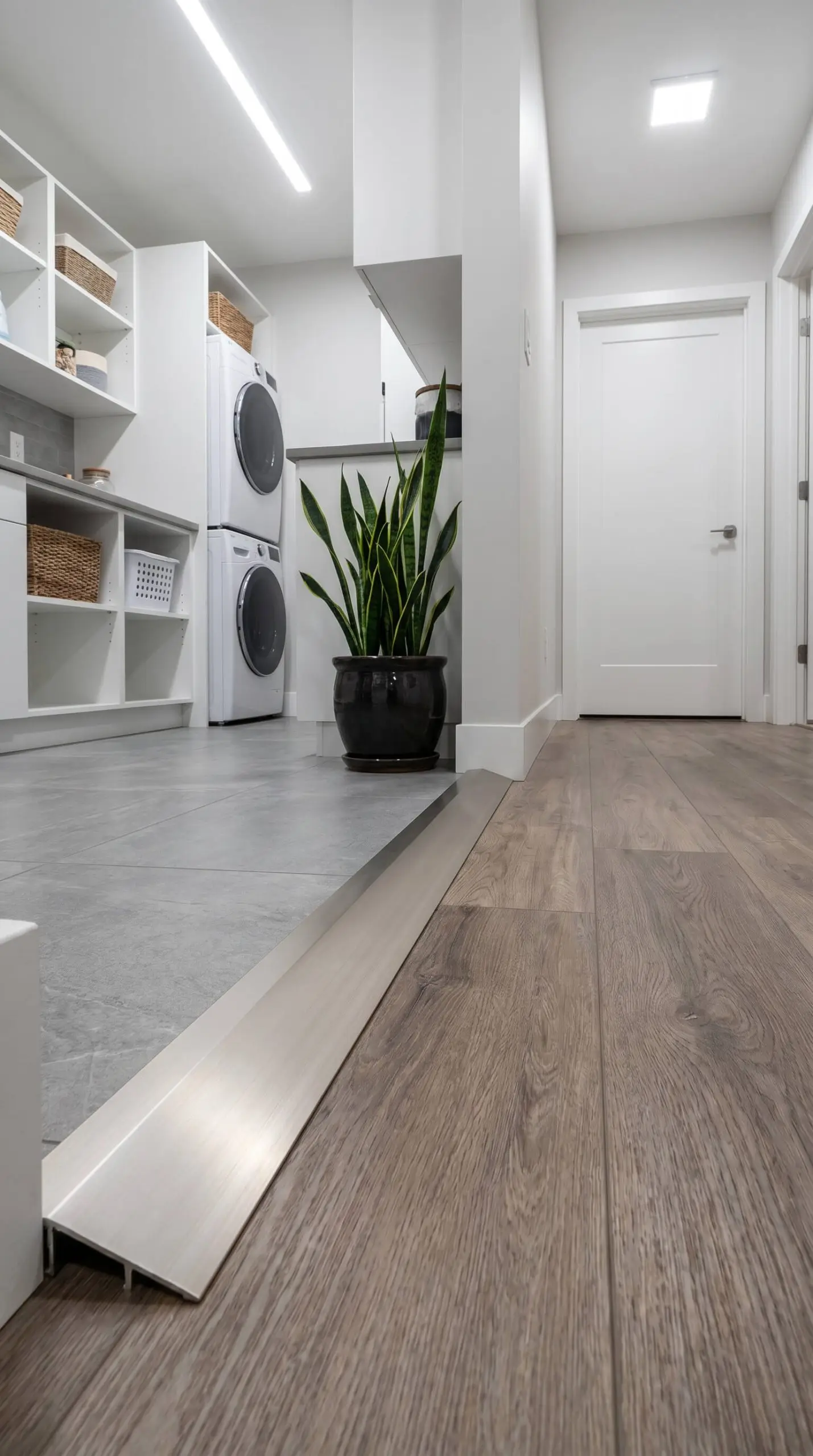 A satin anodized aluminum Schluter-RENO sloped metal profile provides a gentle floor transition from higher porcelain tile down to luxury vinyl plank flooring.