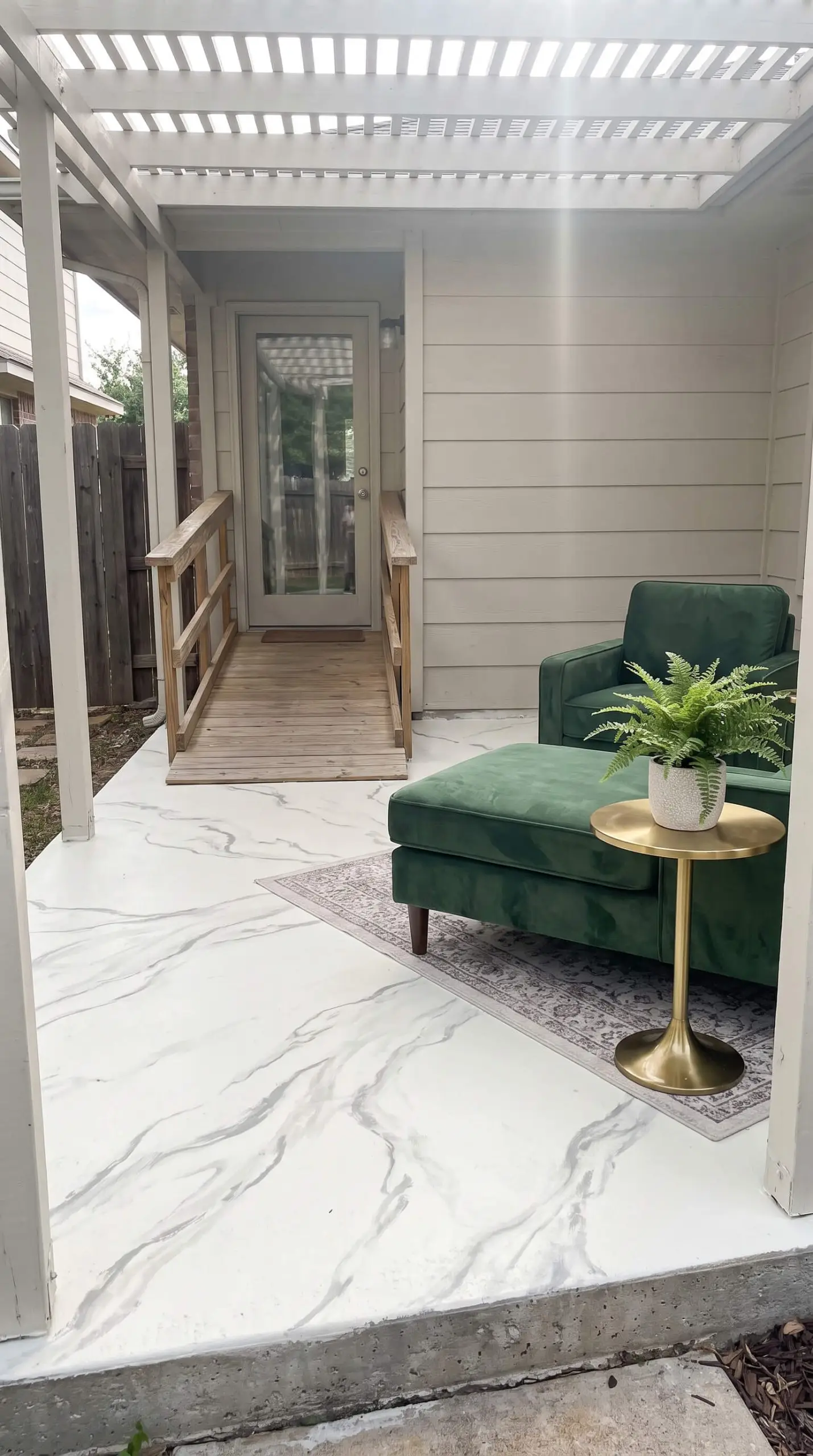 A polished brass accent table and velvet-textured outdoor lounger sit on a faux marble floor showcasing the best Behr patio paint colors.